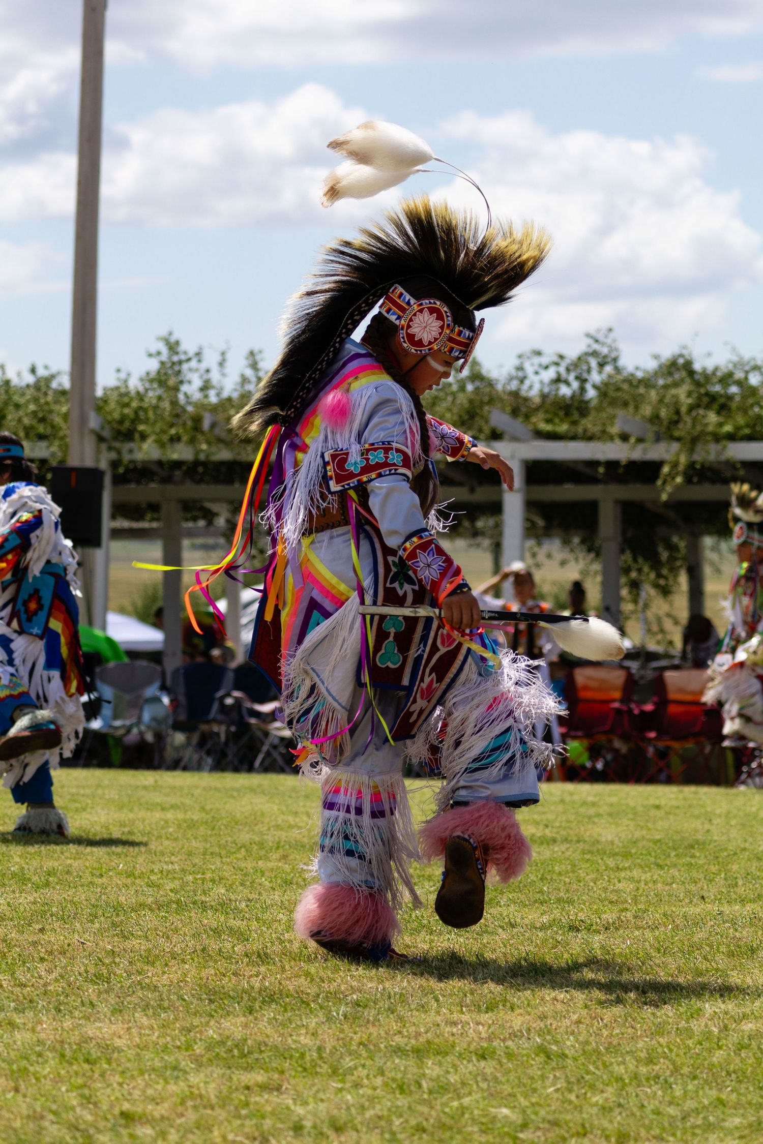 Native American grass dancer in colorful regalia with roach headdress dancing at powwow.