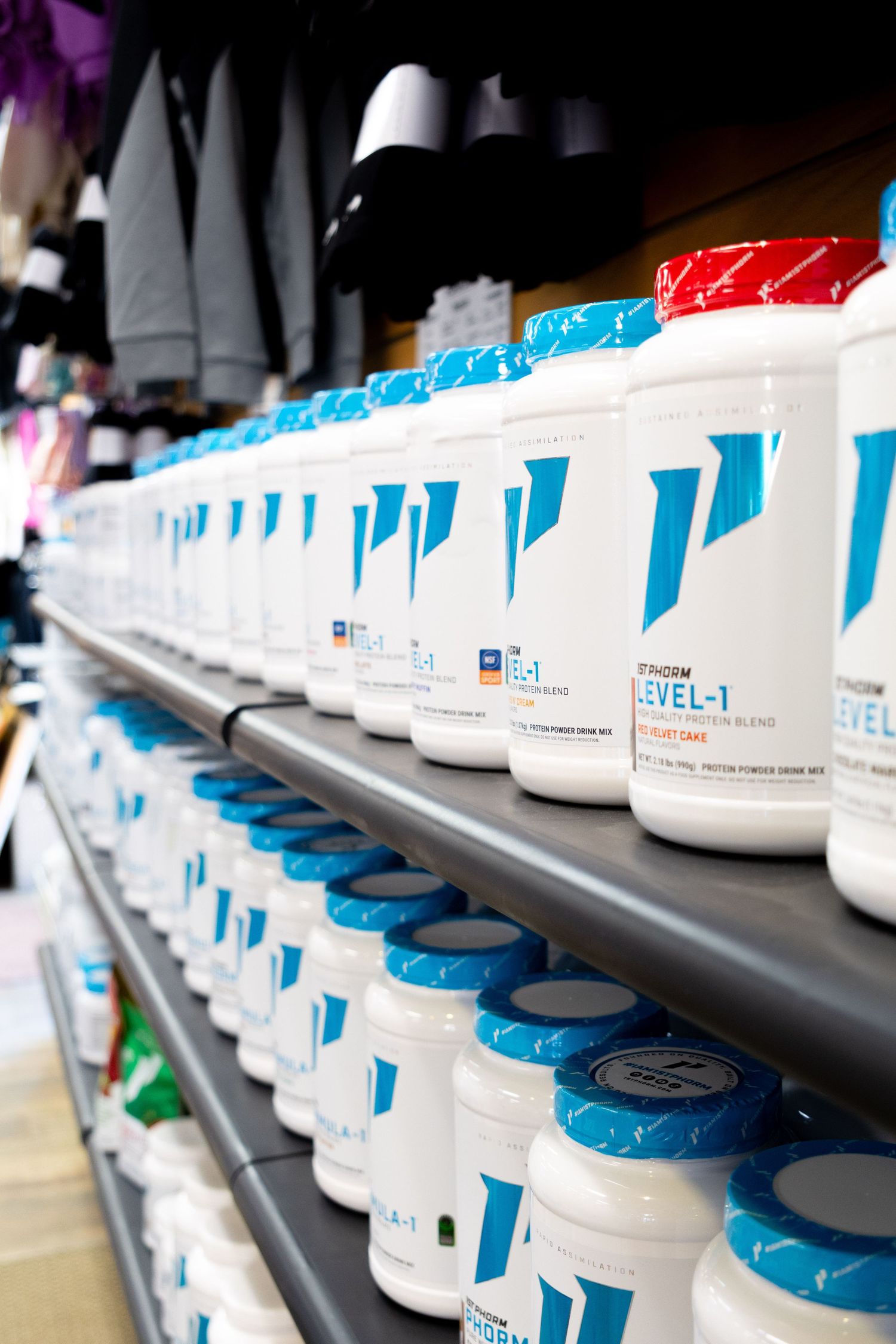 Rows of Phorm Level-1 protein powder supplements with blue lids neatly arranged on store shelves.