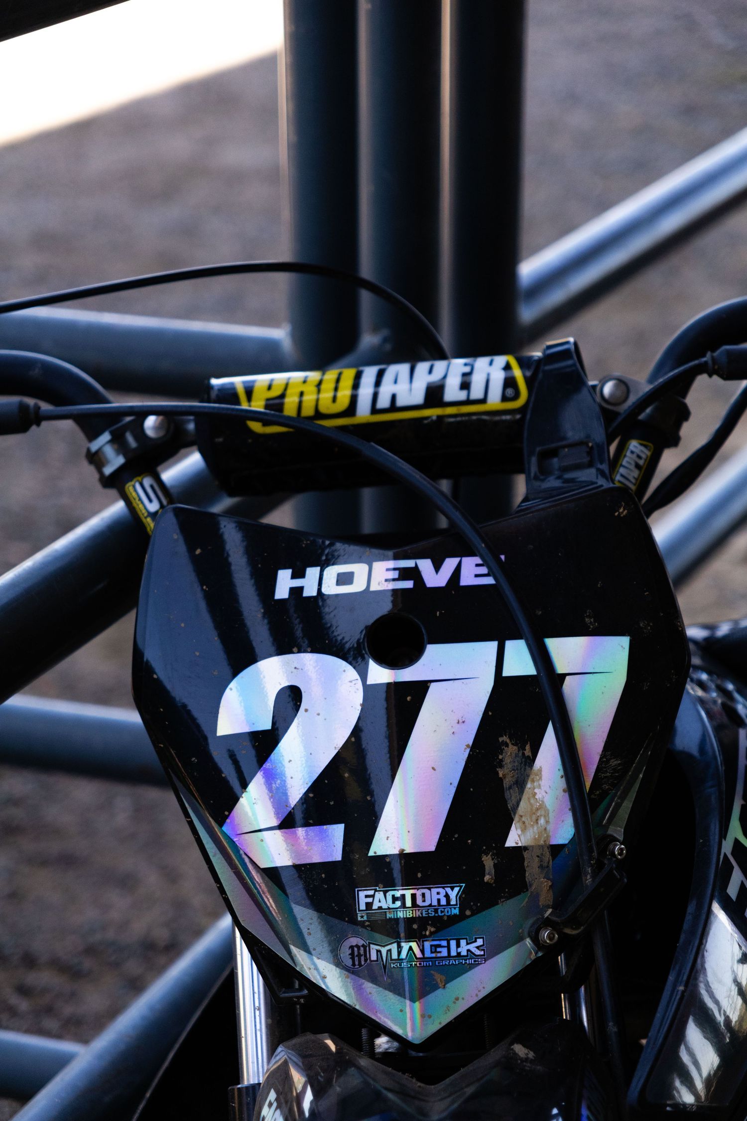 Close-up of a black iridescent number 277 Hoeve Factory motocross bike number plate with Pro Taper bar.