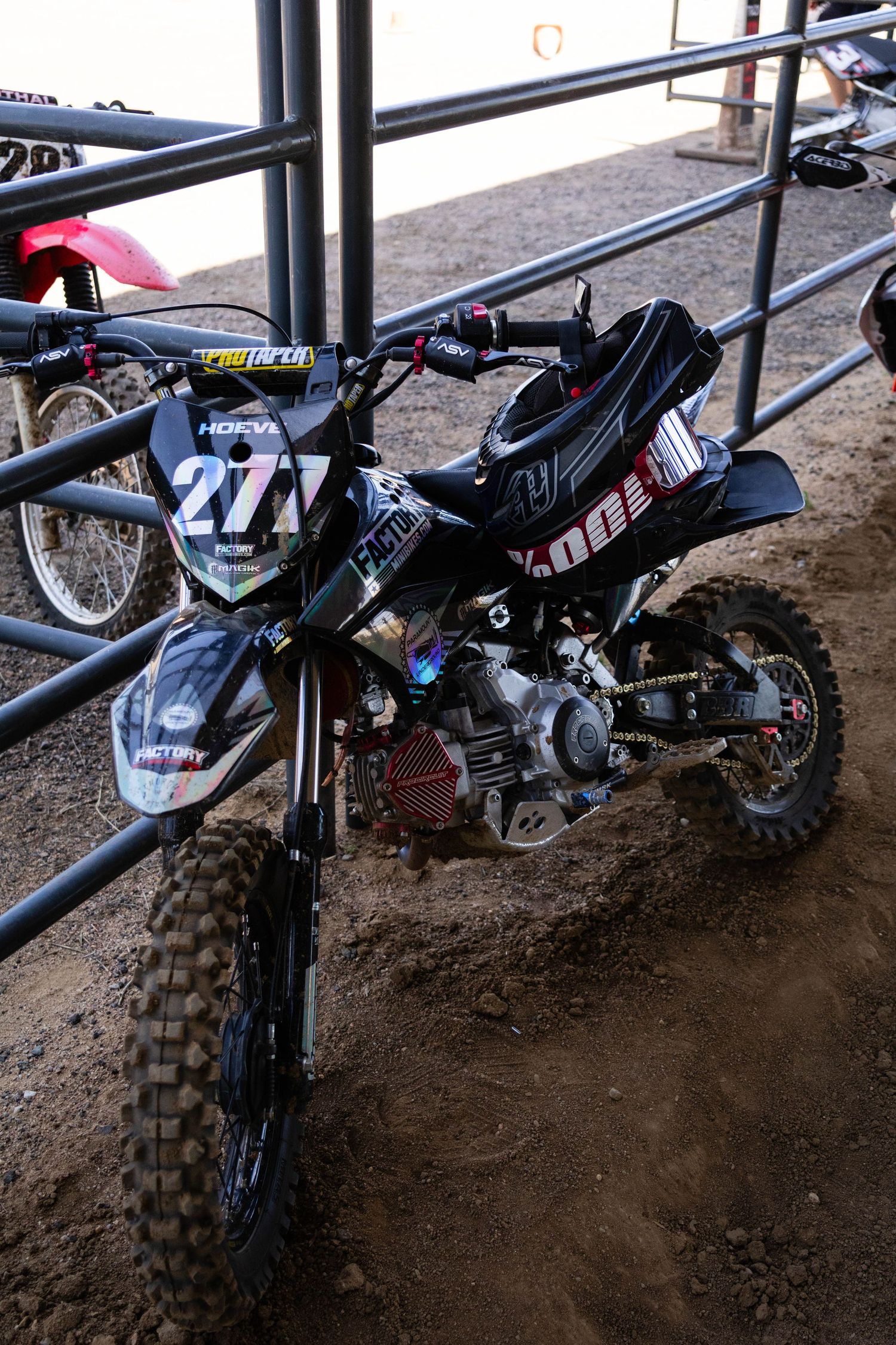 Black number 277 Hoeve motocross dirt bike with Pro Taper handlebars parked against metal rails.