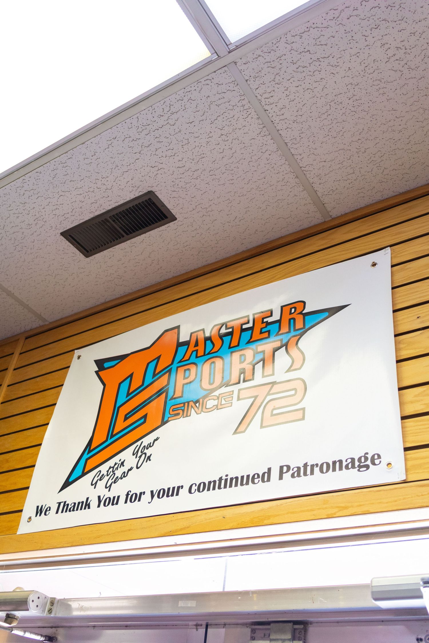 Master Sports since 1972 store sign thanking customers for their continued patronage mounted on wooden wall.