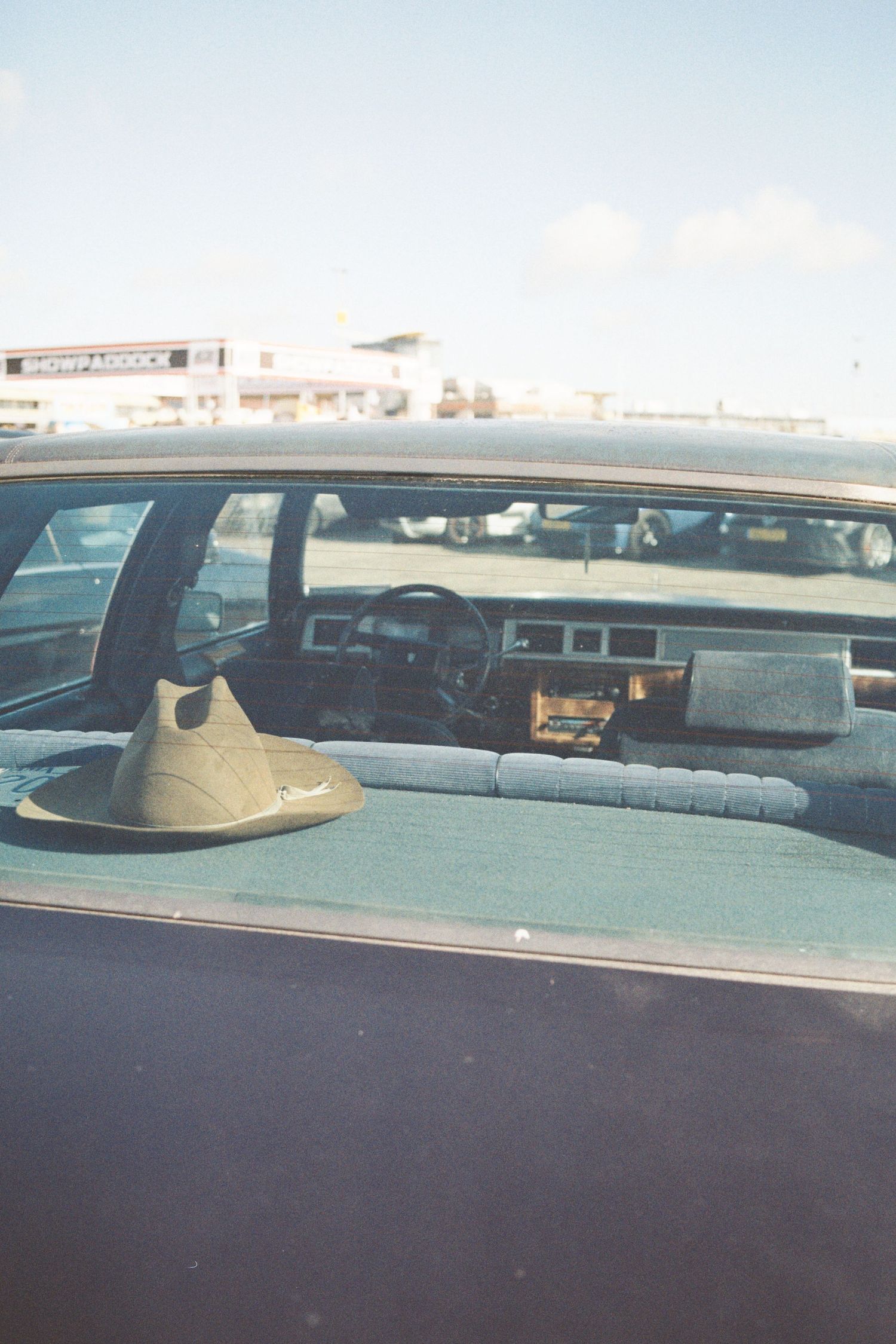 Vintage American car interior viewed through window with cowboy hat on rear shelf.