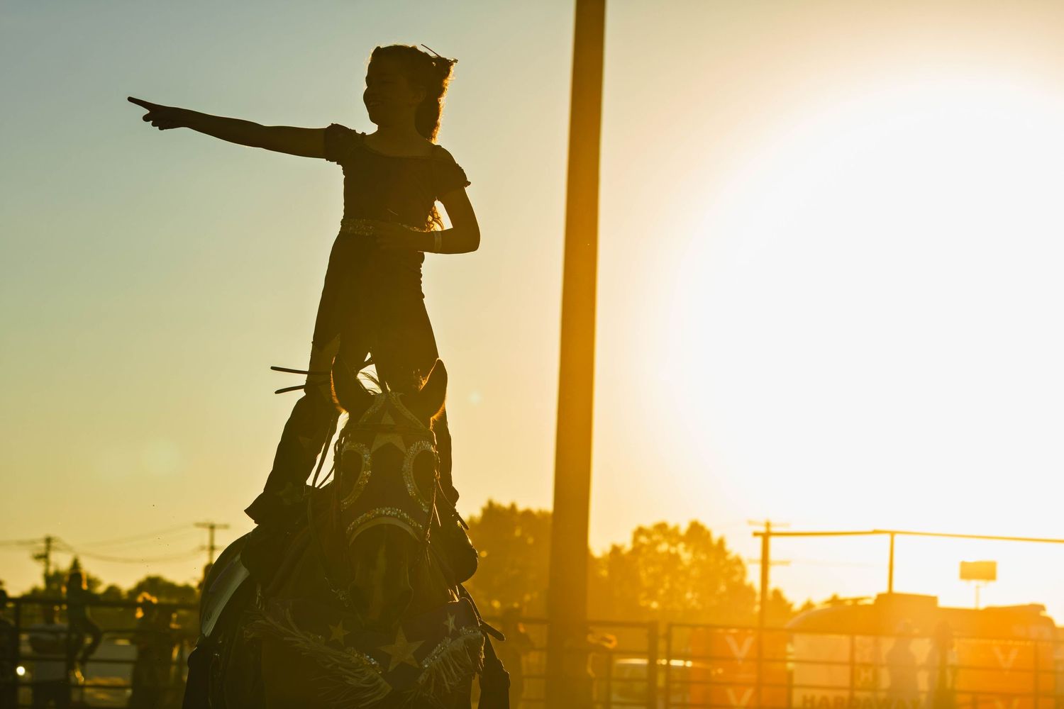Silhouette of a cowboy on horseback statue pointing forward against a golden sunset sky.
