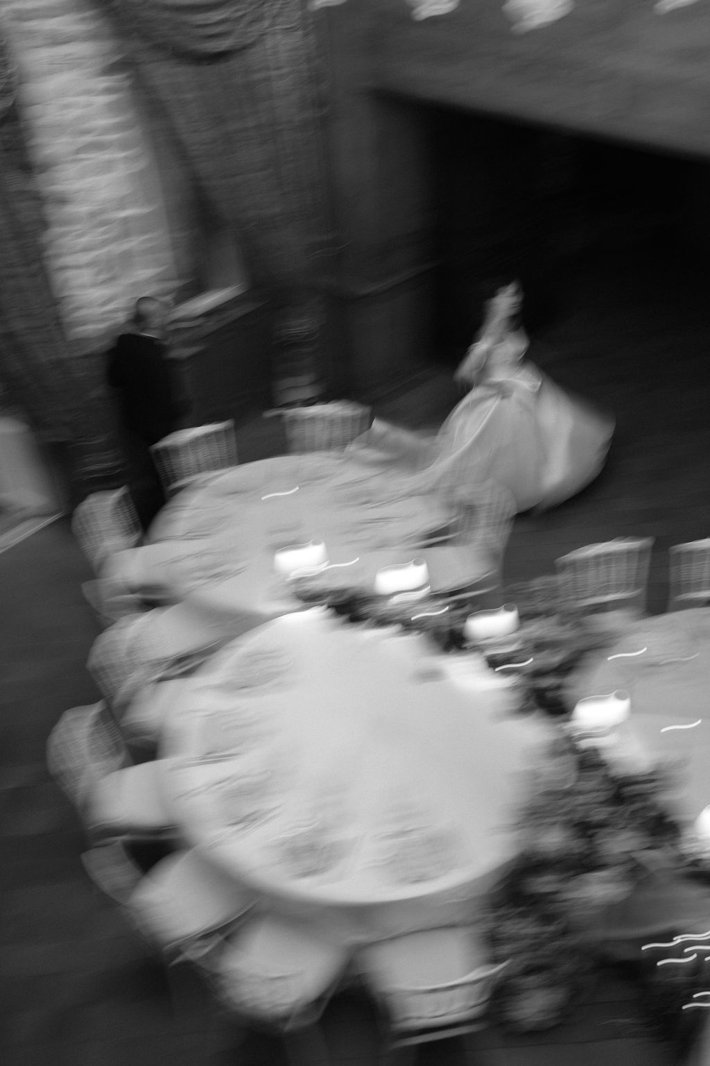 Blurred black and white aerial shot of bride and groom at candlelit wedding reception.