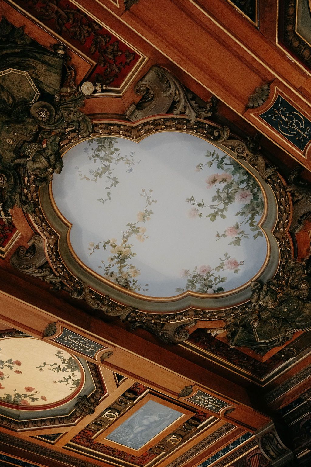 Ornate painted ceiling with floral motifs in an elegant French baroque interior.