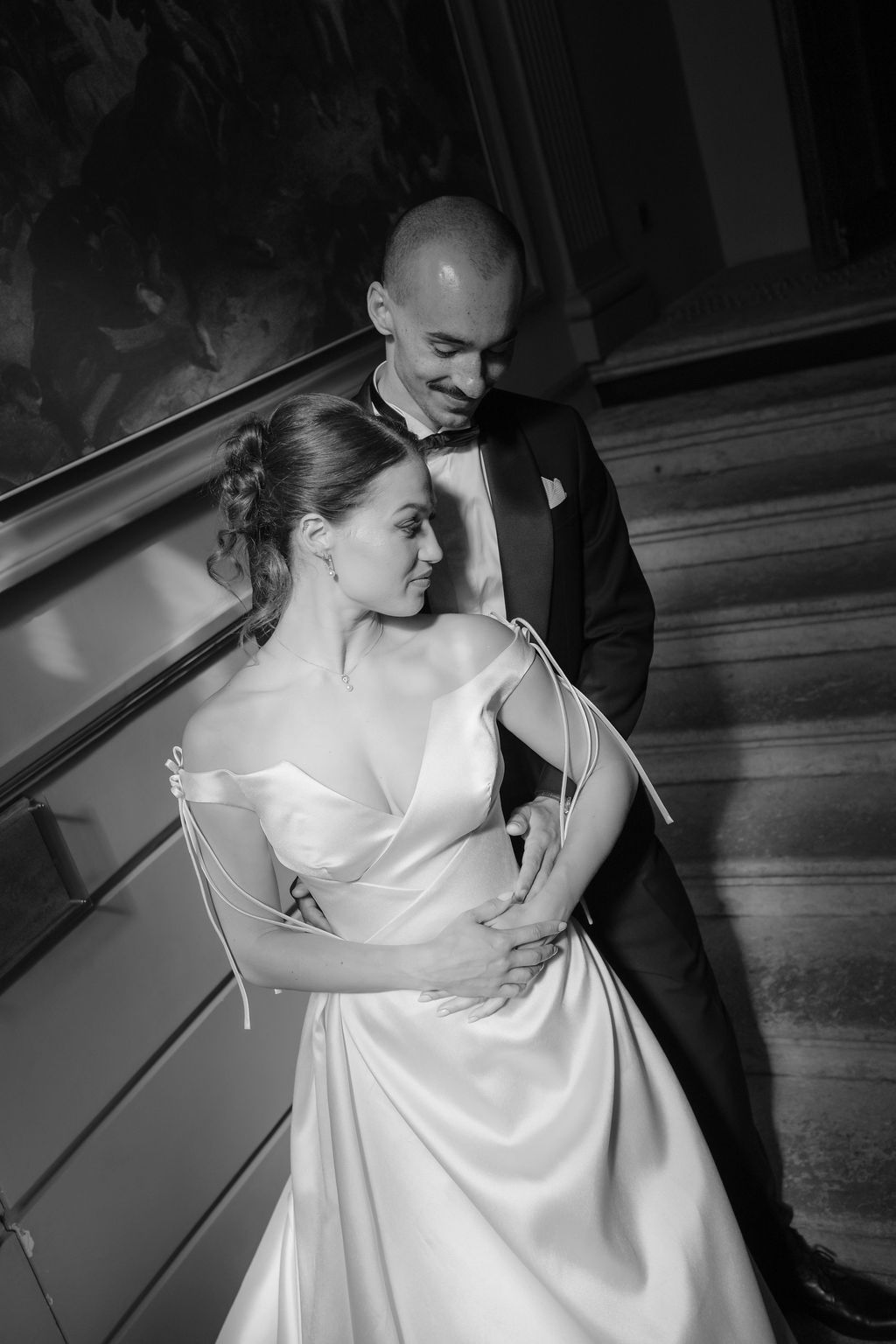 Black and white portrait of bride and groom embracing tenderly on grand chateau staircase.