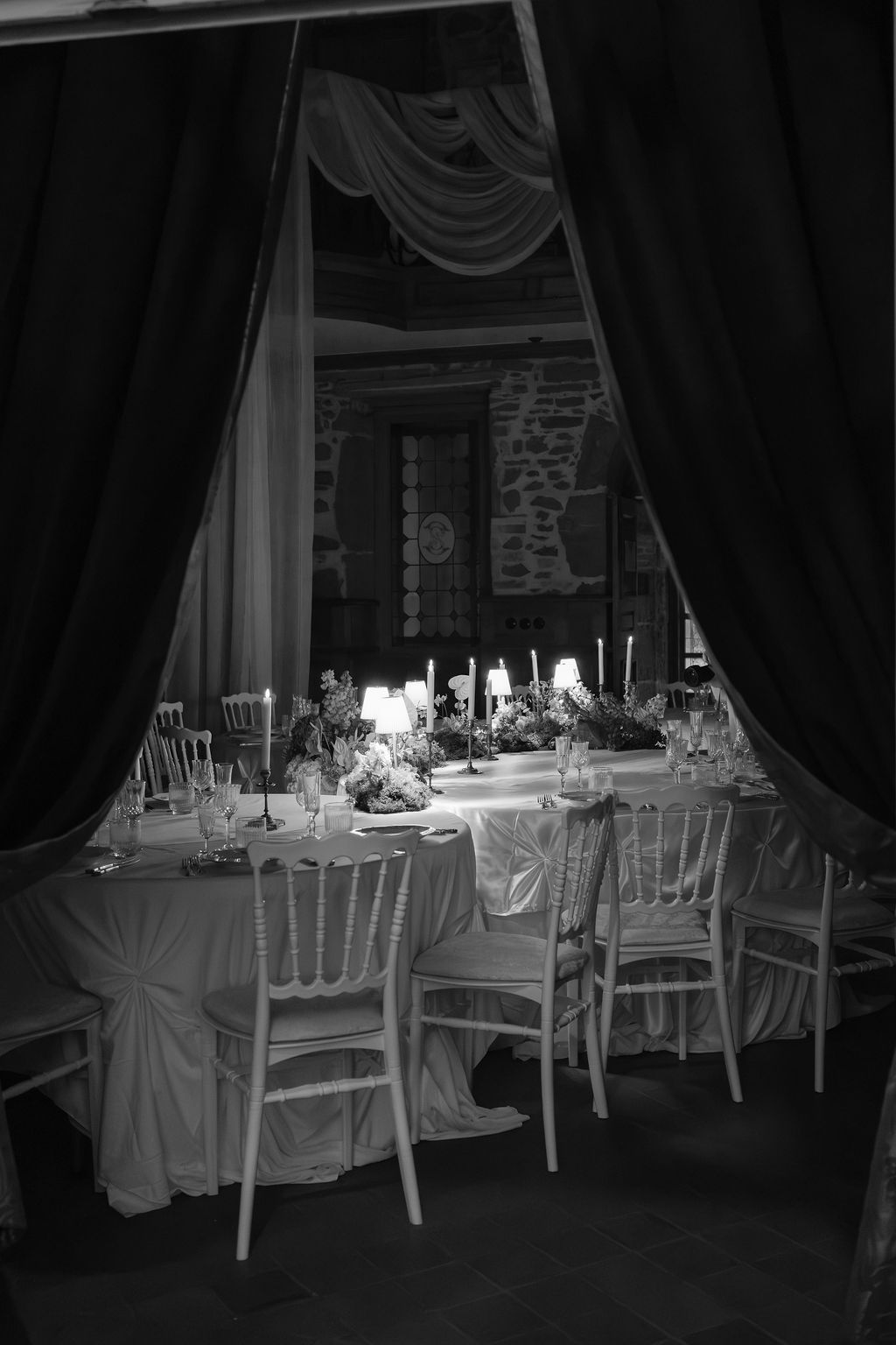 Black and white photo of a laughing bride and groom sharing a joyful moment outdoors.