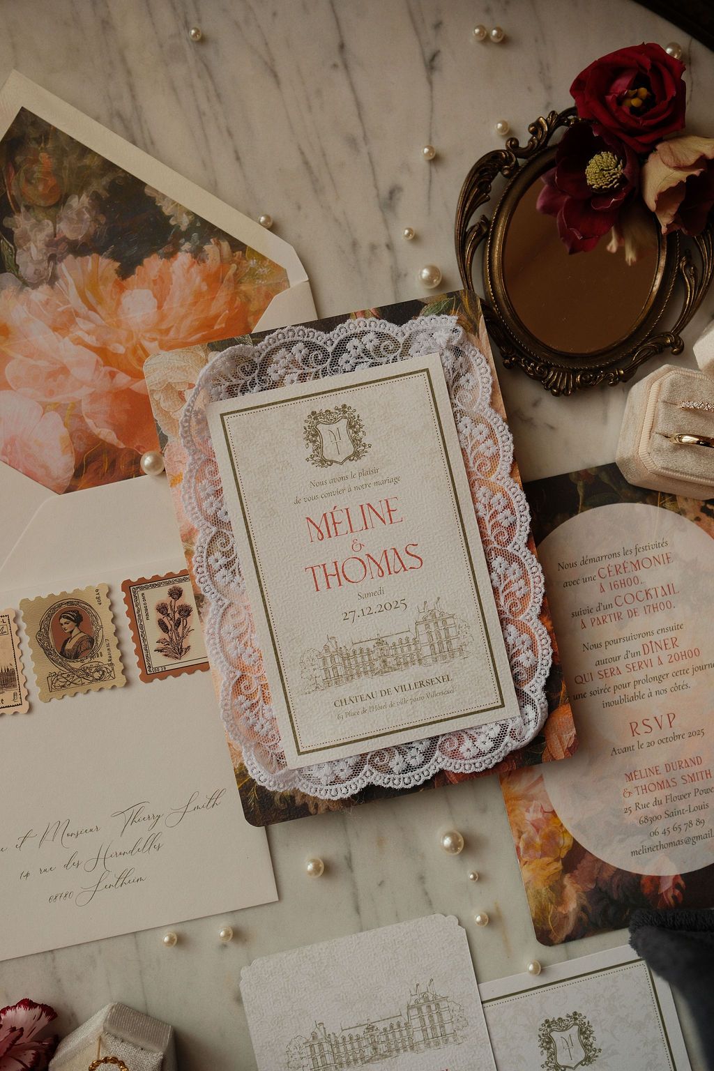 Elegant wedding invitation suite for Meline and Thomas displayed on marble with florals and pearls.