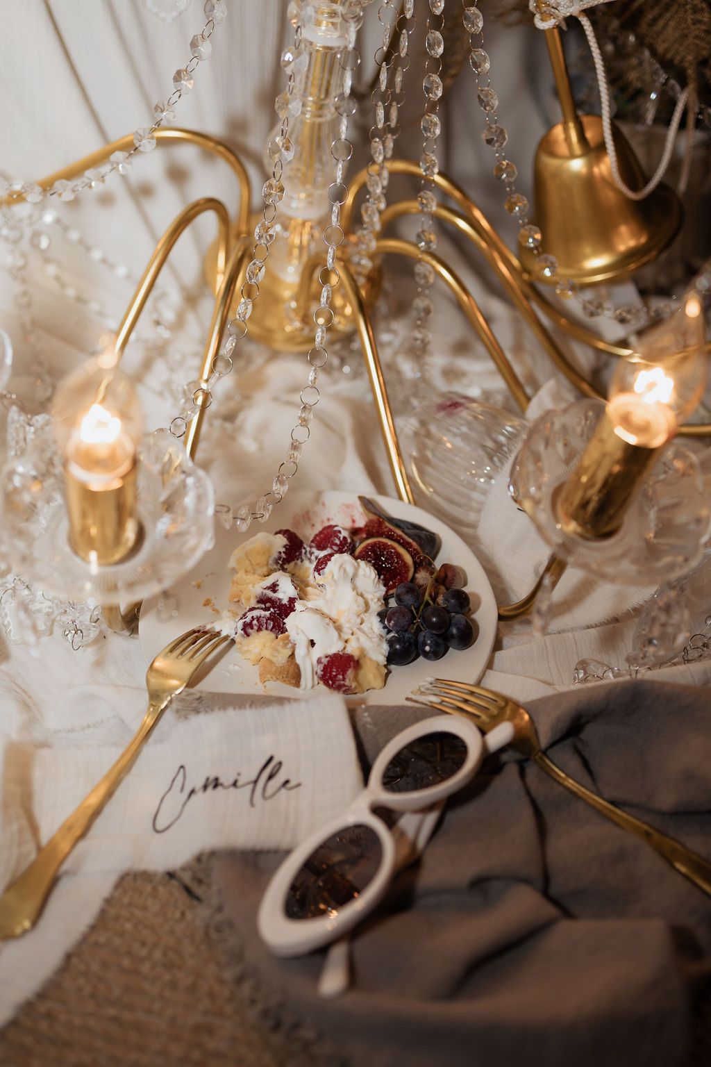 Elegant wedding table setting with gold candelabra, crystal beads, fruit plate, and personalized name card.