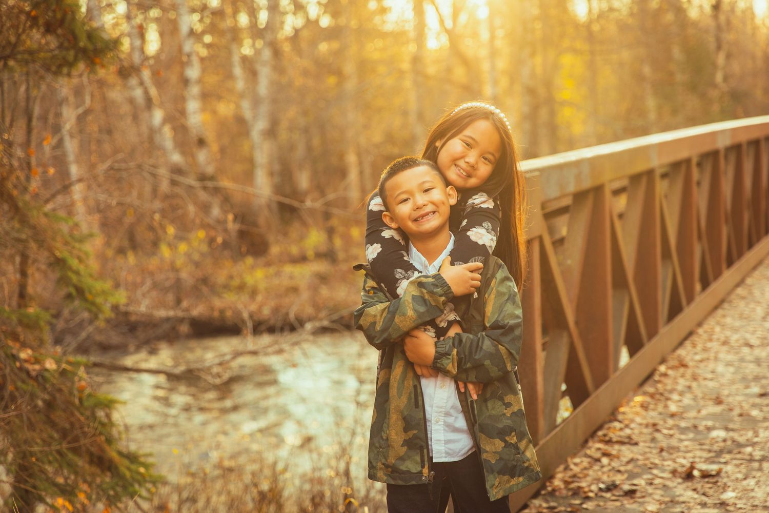 Joyful moment shared on wooden bridge during golden autumn afternoon.