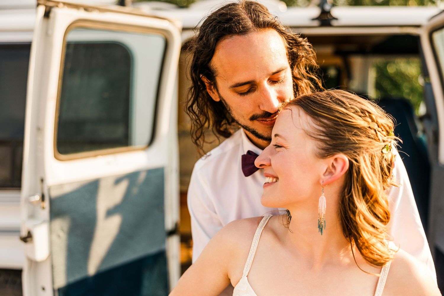 A couple shares a joyful moment together outdoors, both laughing and embracing in natural lighting.