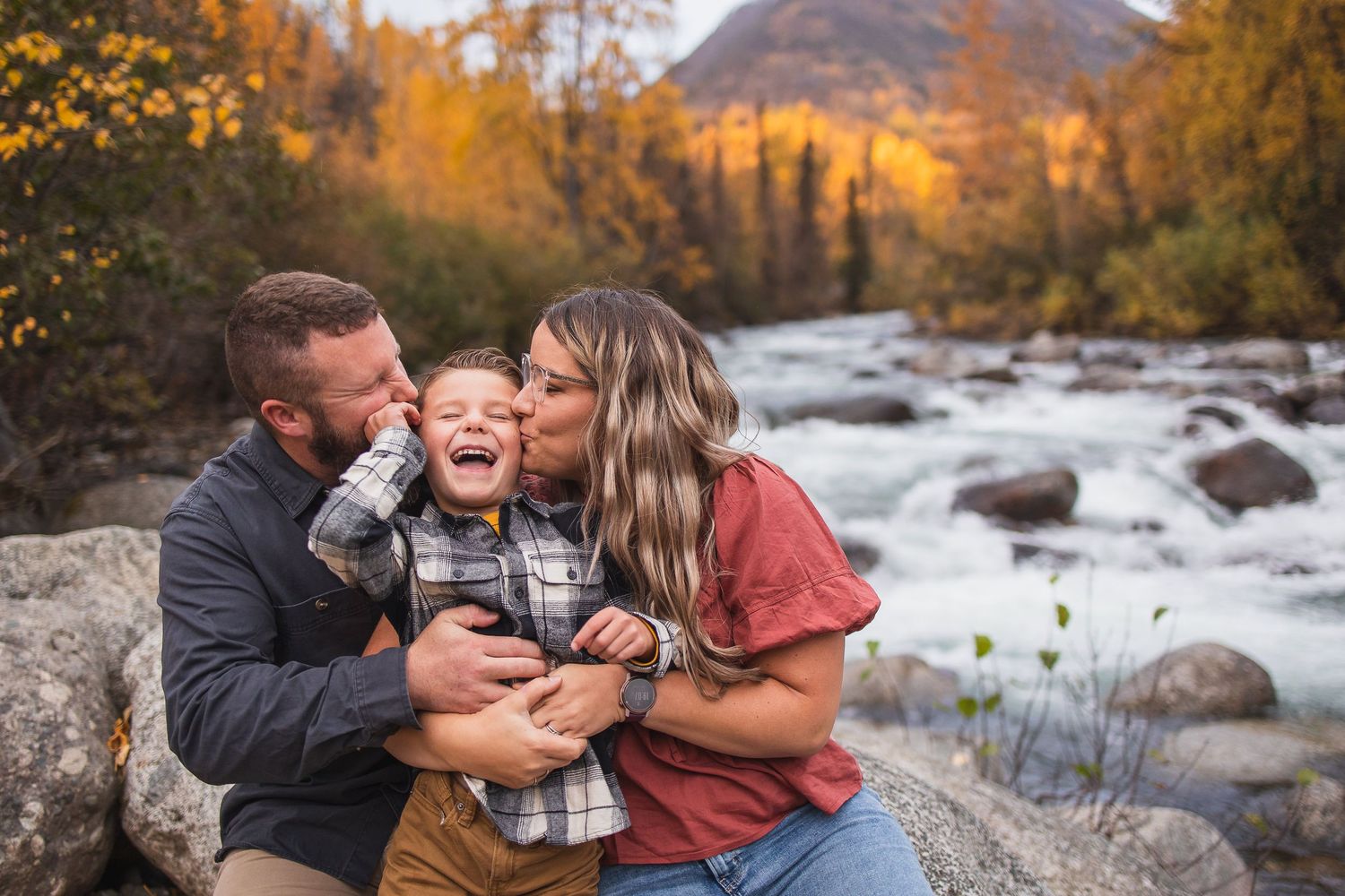 Family sharing joyful moments together by a rocky stream during golden fall sunset.