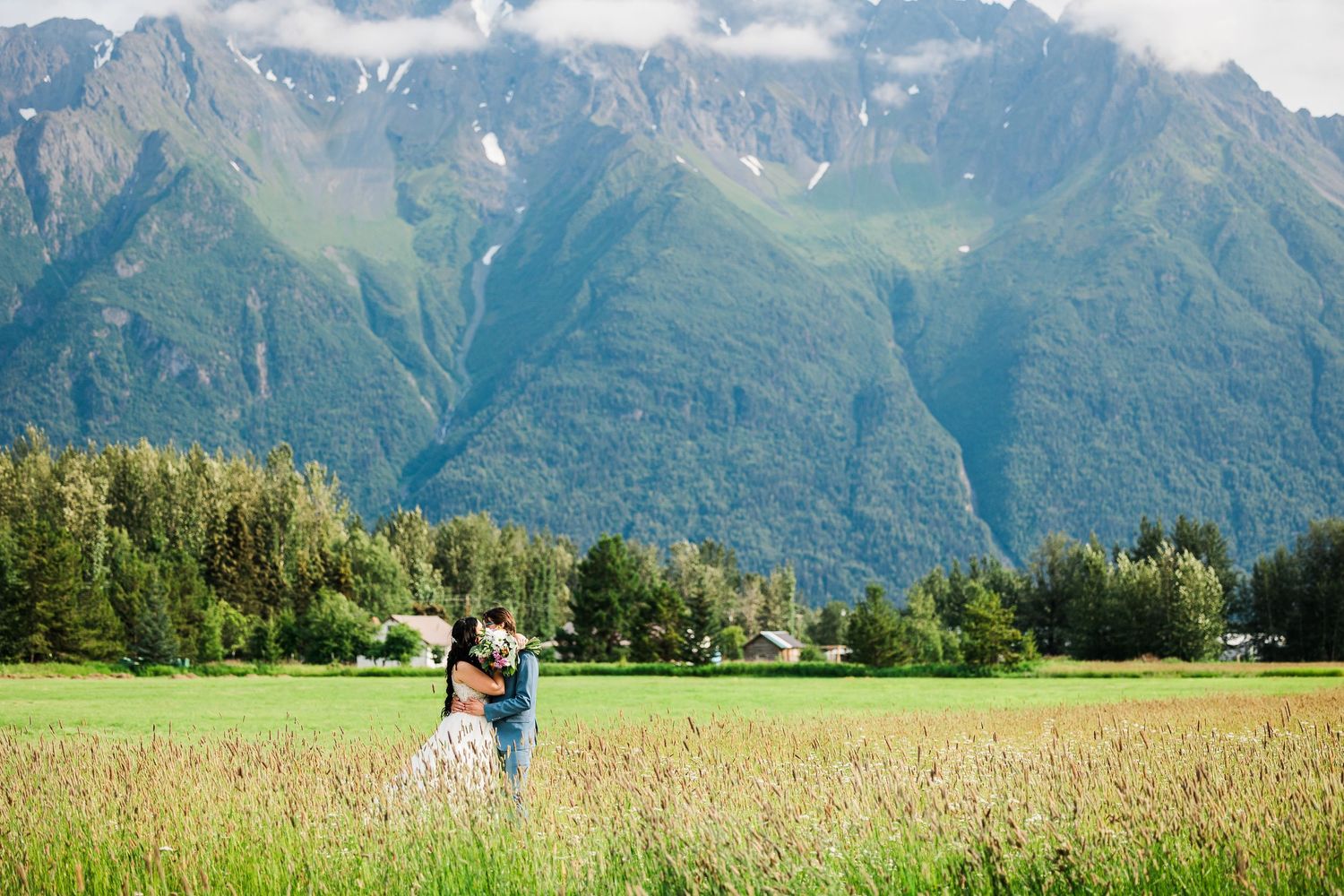 Scenic mountain landscape with snow-capped peaks and green meadows in the foreground on a sunny summer day.