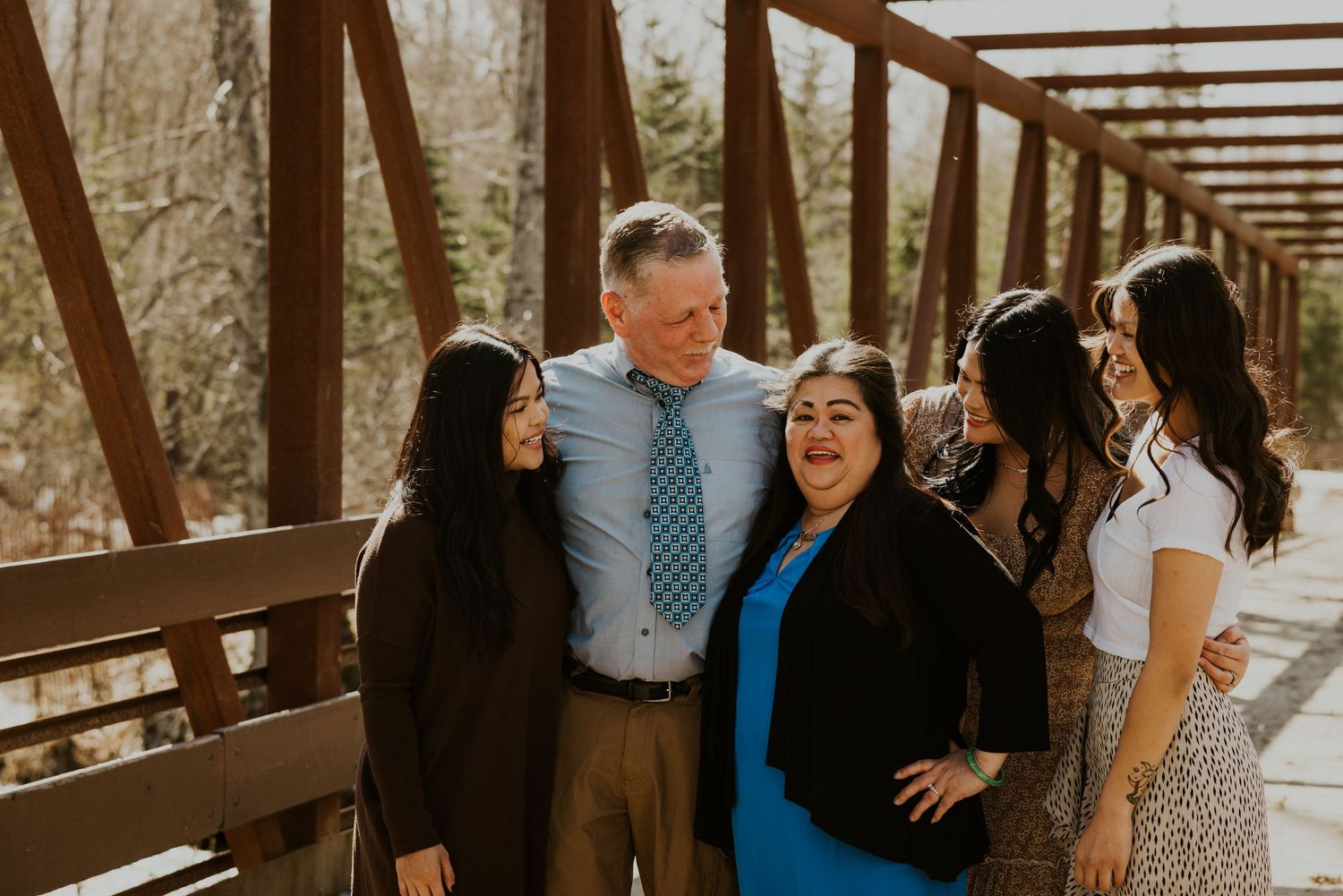 Group sharing laughs together on rustic wooden bridge during sunny afternoon.