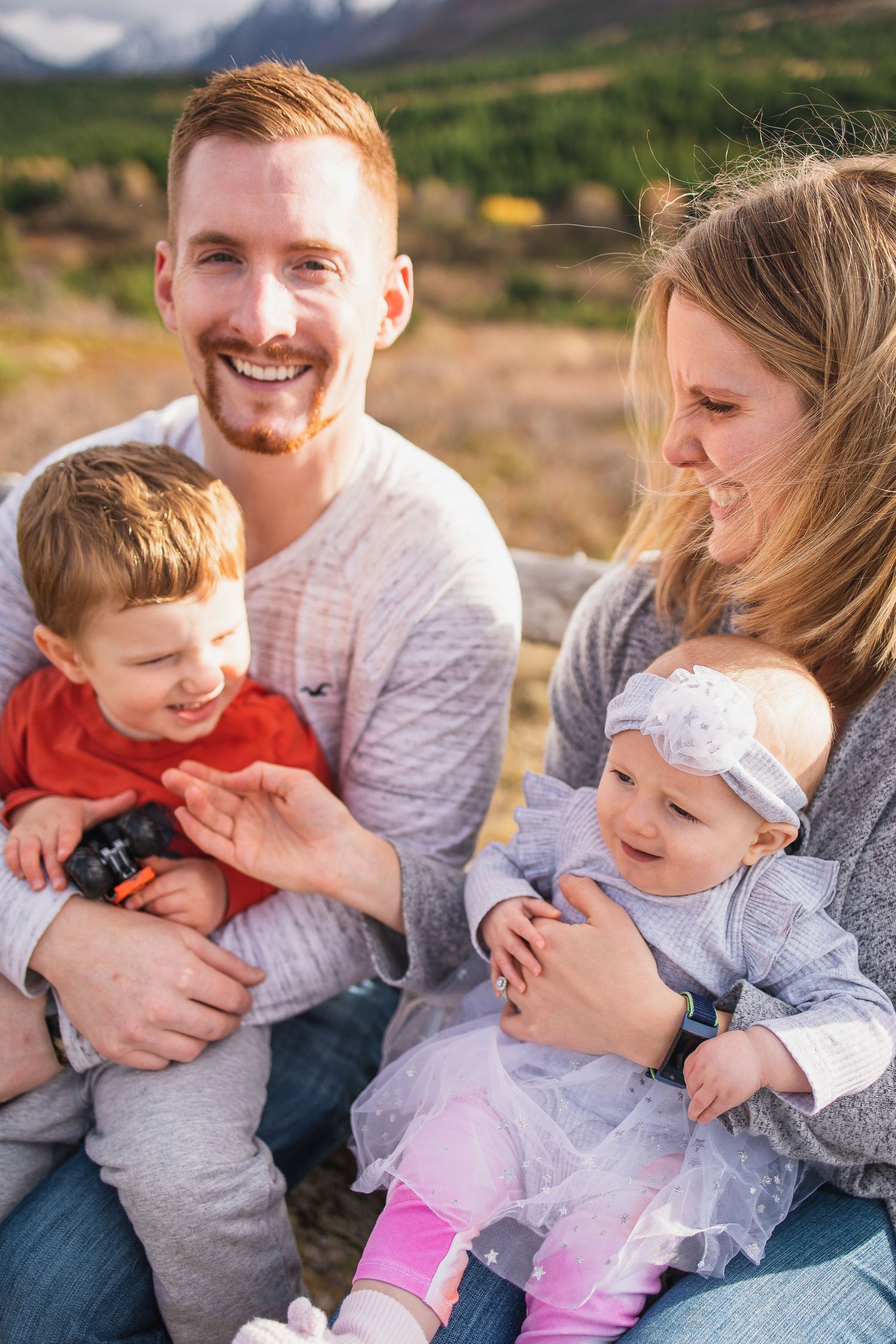 Happy family enjoying quality time together outdoors with mountain scenery in the background.