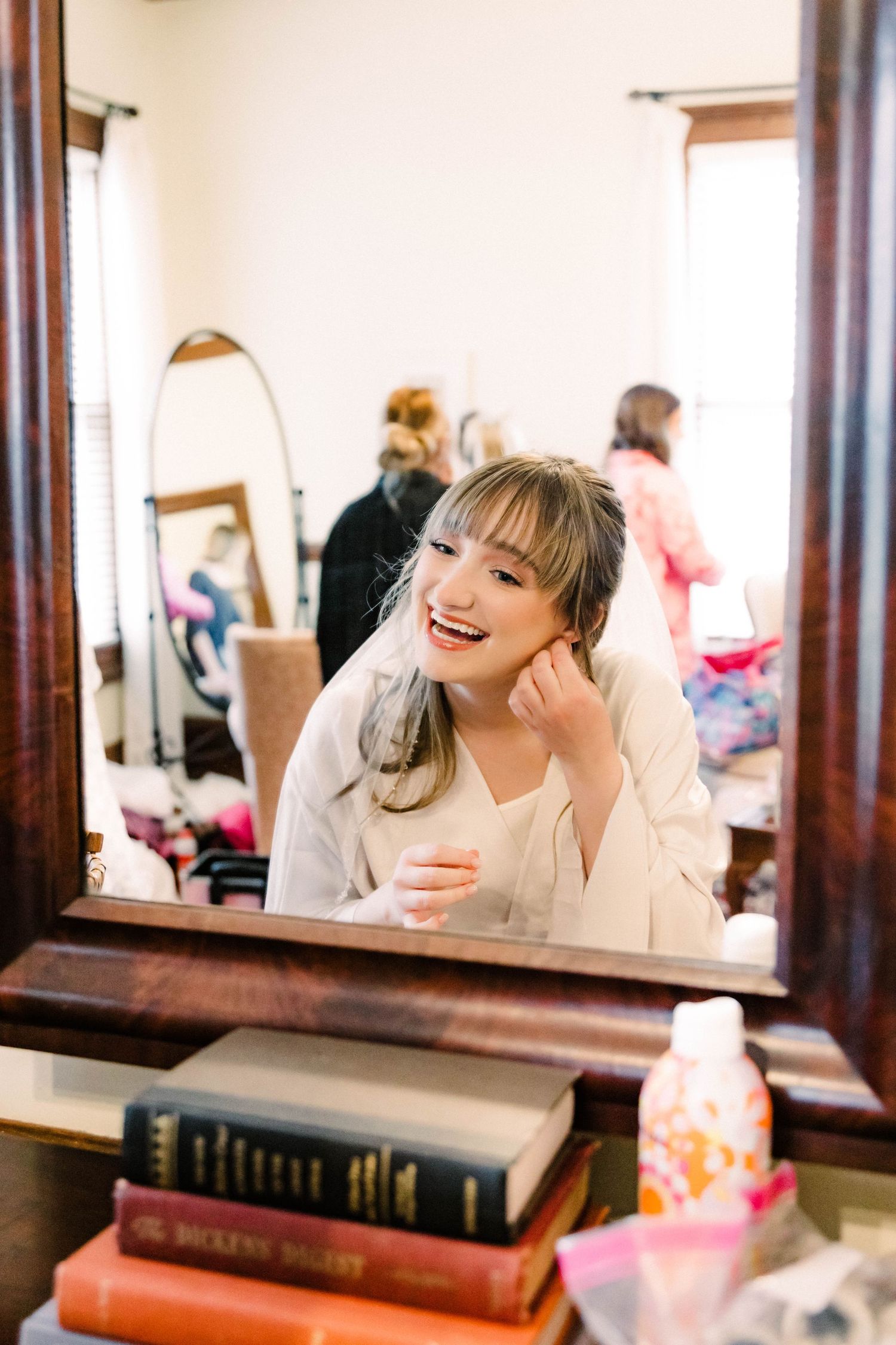 A joyful smile reflected in a vintage vanity mirror with books and decor items on the dresser.