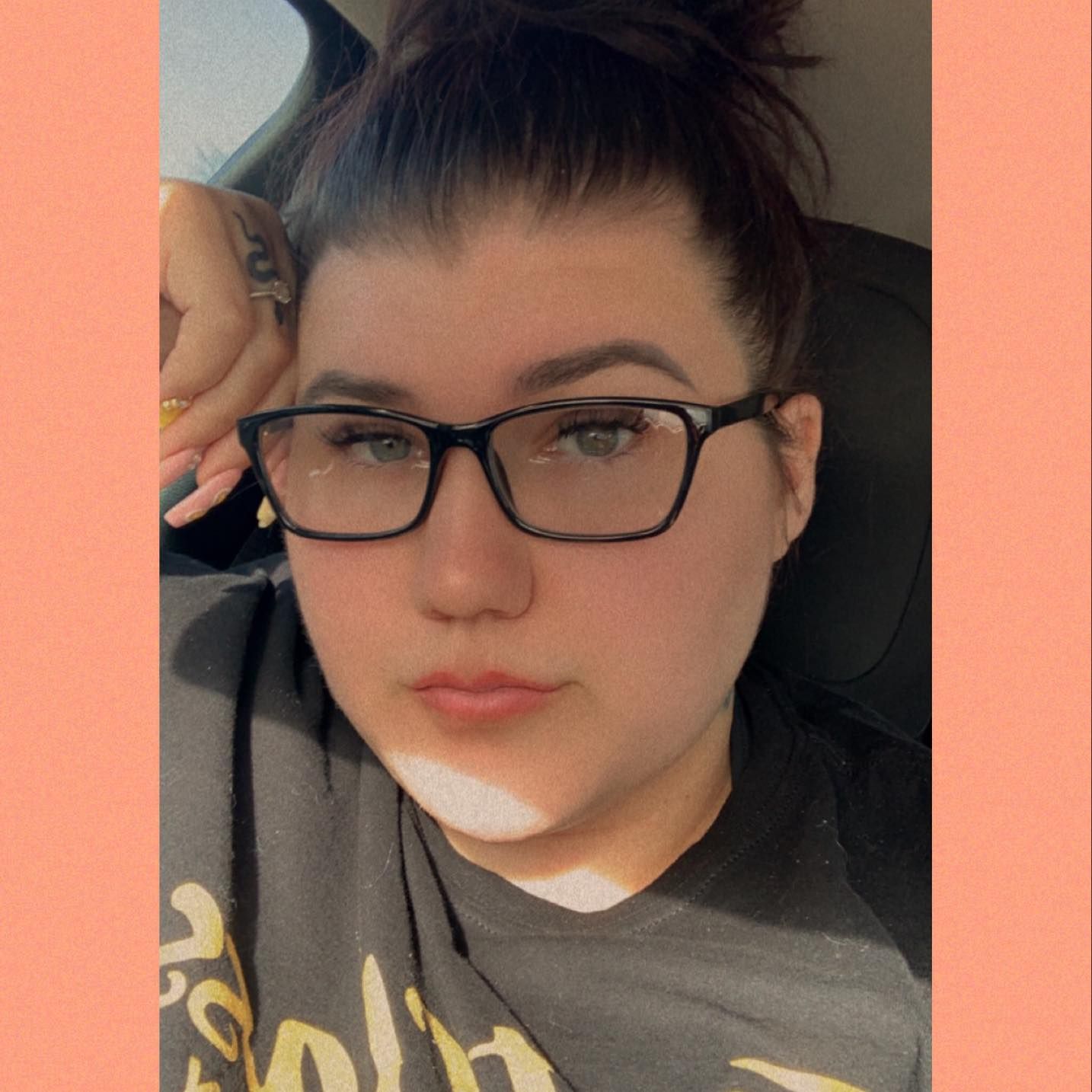 A selfie taken from a car seat showing Kristin from desert bloom photo + travel co wearing black-framed glasses and a grey t-shirt.