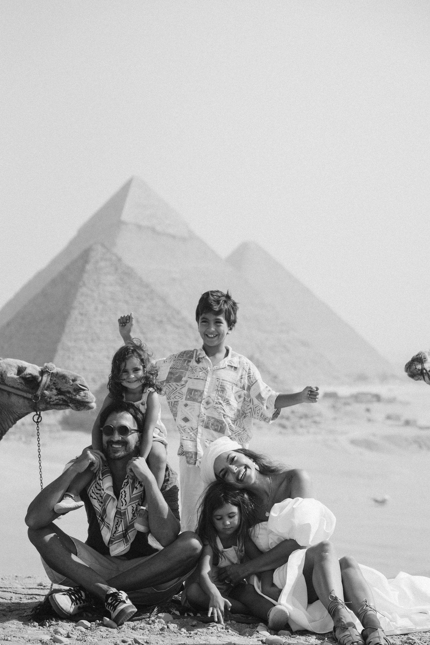 Three vintage black and white photos show tourists posing playfully in front of the Egyptian pyramids.