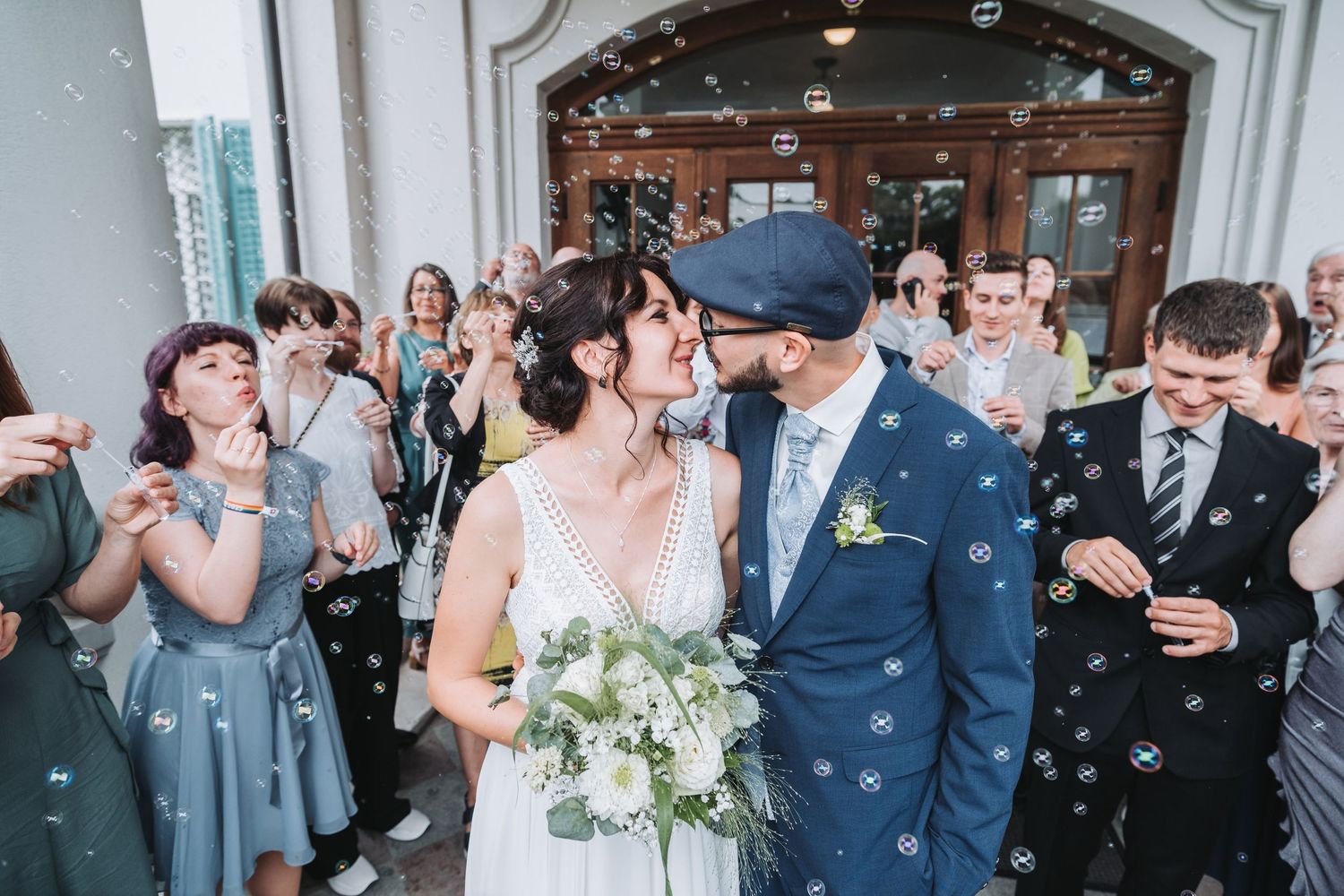 Wedding celebration with guests throwing confetti outside historic building entrance.