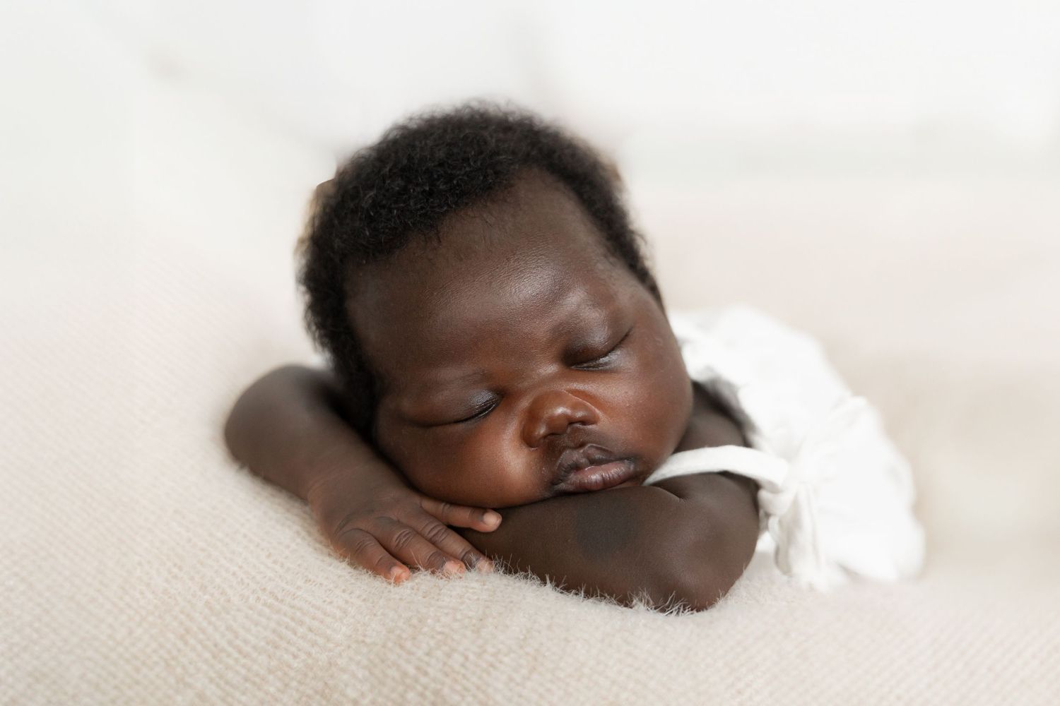 Sleeping baby peacefully rests on soft beige fabric in gentle natural light.