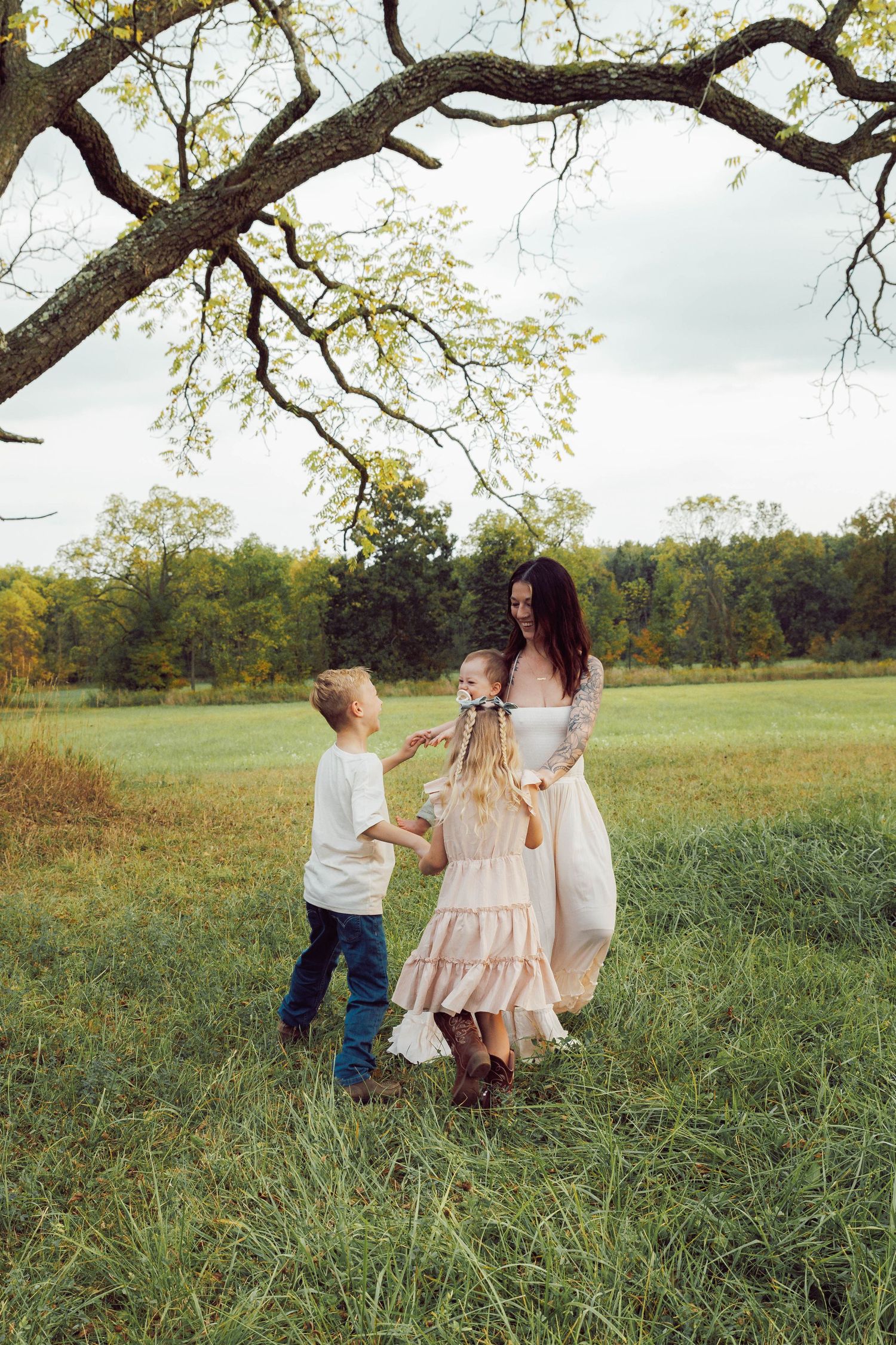 Dreamy family session in Howell, Michigan with mom and two kids playing at sunset in a field, photographed by Brena B Imagery.