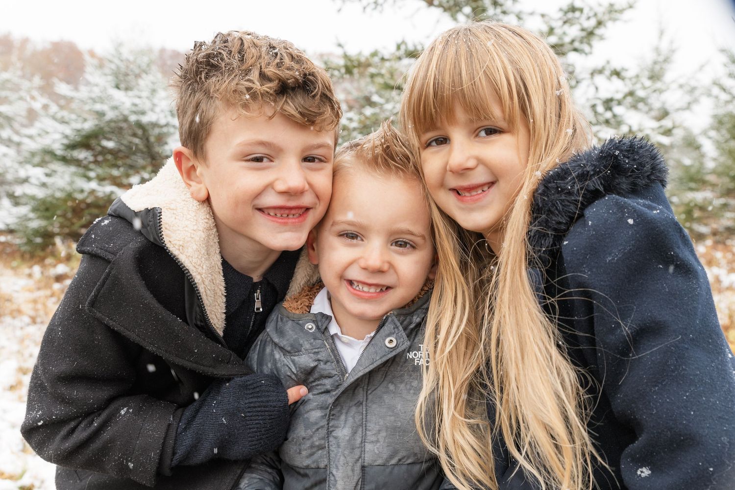 Family portrait session in Fenton, Michigan during winter at a Christmas tree farm, children smiling, photographed by Brena B Imagery.