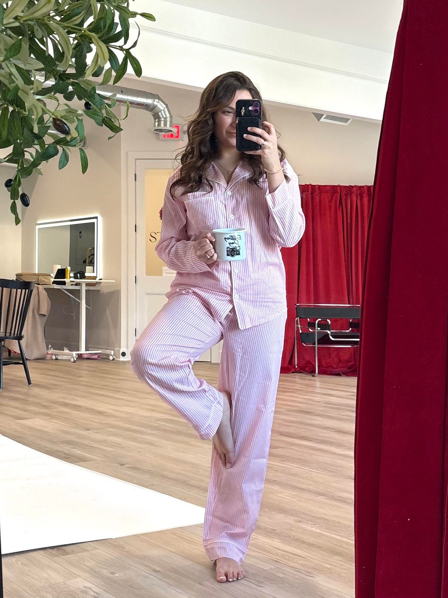 Photographer Brena B Imagery in pajamas editing photos with a coffee mug.