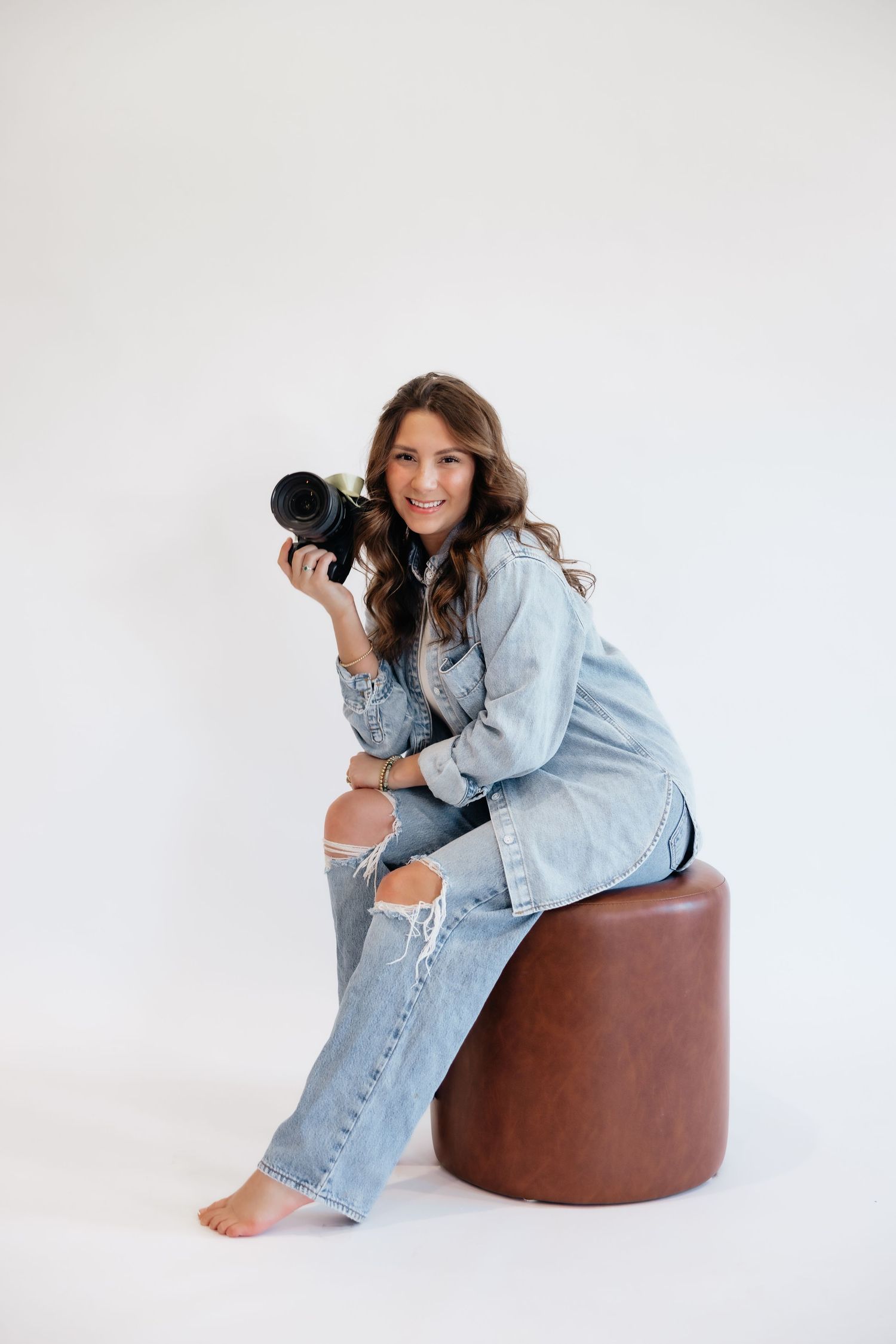 Brena B Imagery Howell, Michigan senior and wedding photographer wearing denim in photography branding session posing on a stool.