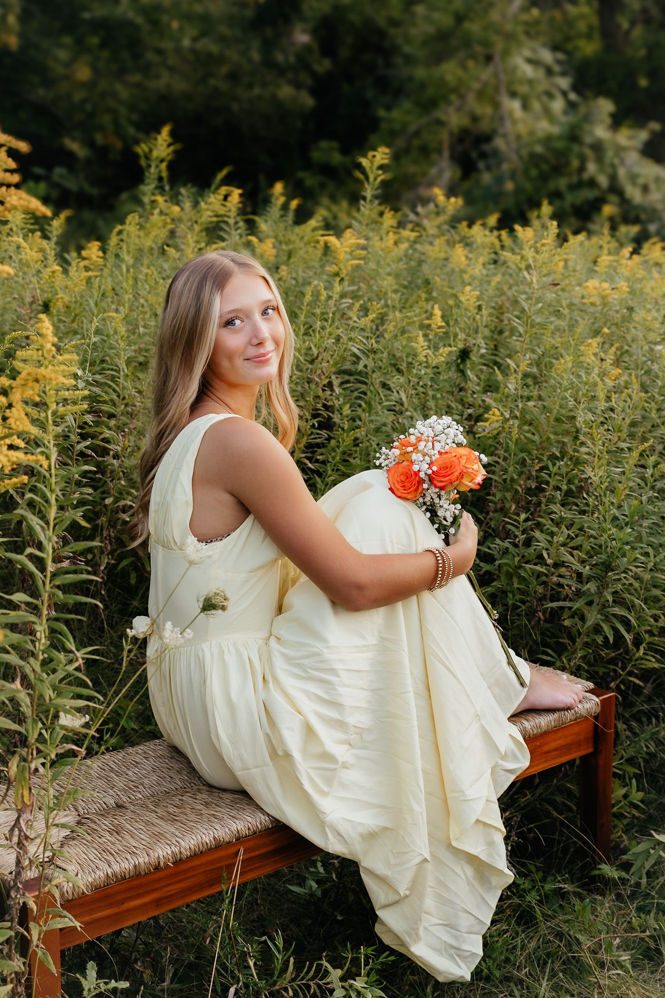 Dreamy golden hour senior photography session by Howell, Mi Senior Photographer Brena B Imagery. Senior sits on bench in field. Senior Inspo