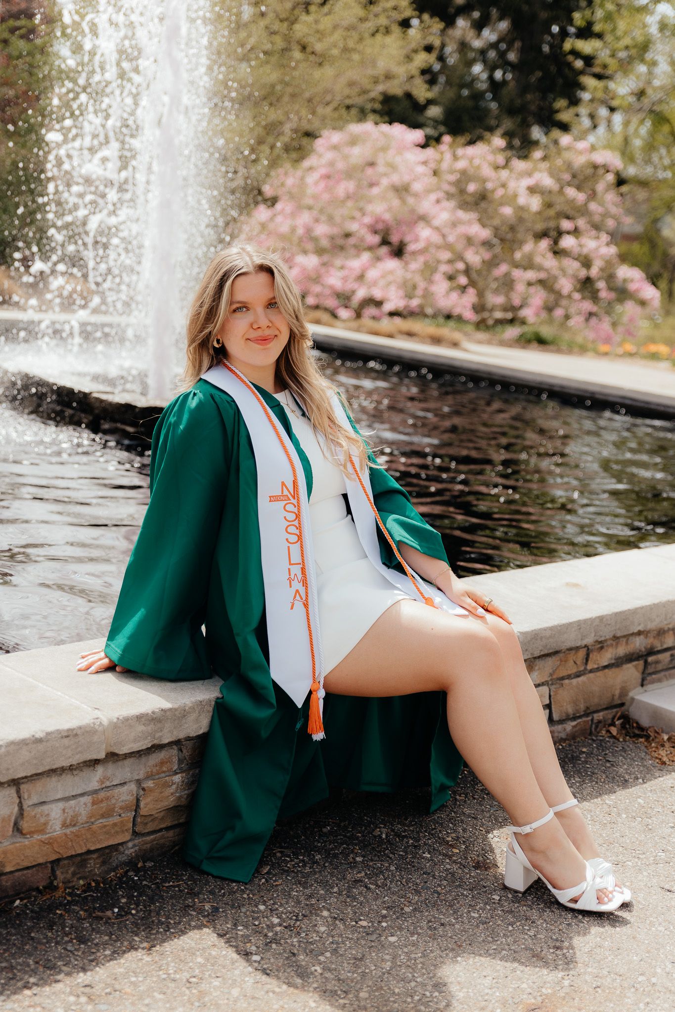 MSU graduation portrait of a girl sitting at the fountain in East Lansing, Michigan, photographed by Brena B Imagery.