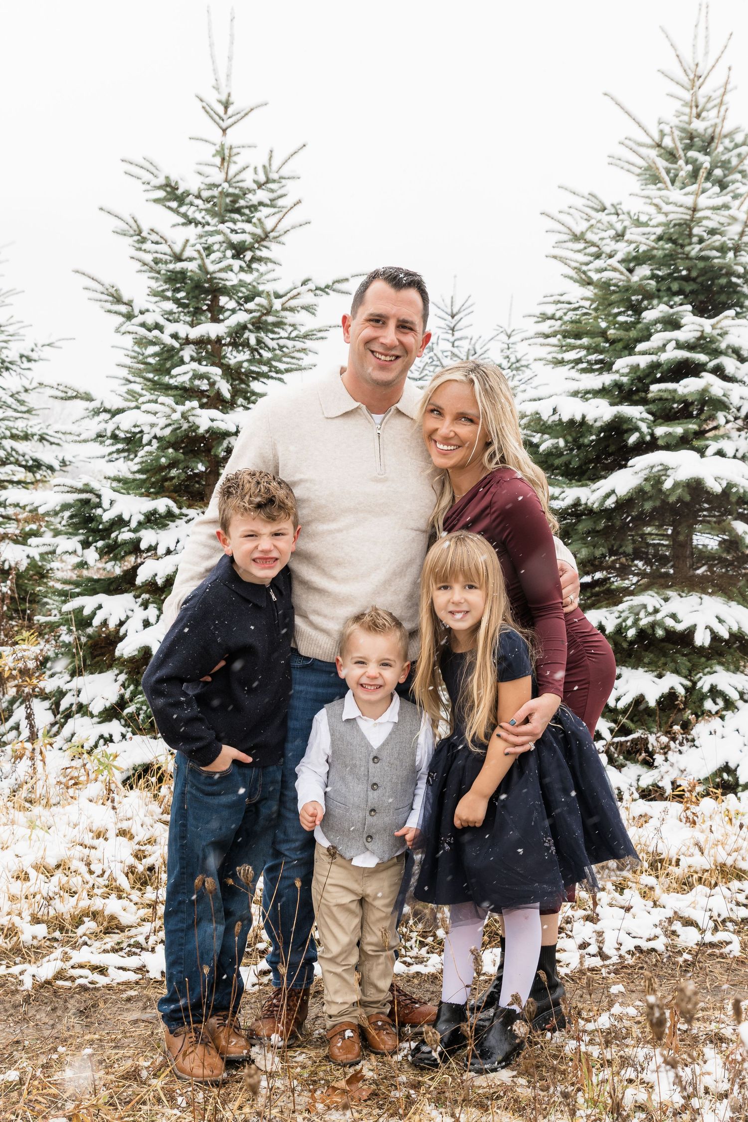 Family portrait session in Fenton, Michigan during winter at a Christmas tree farm, family smiling, photographed by Brena B Imagery.