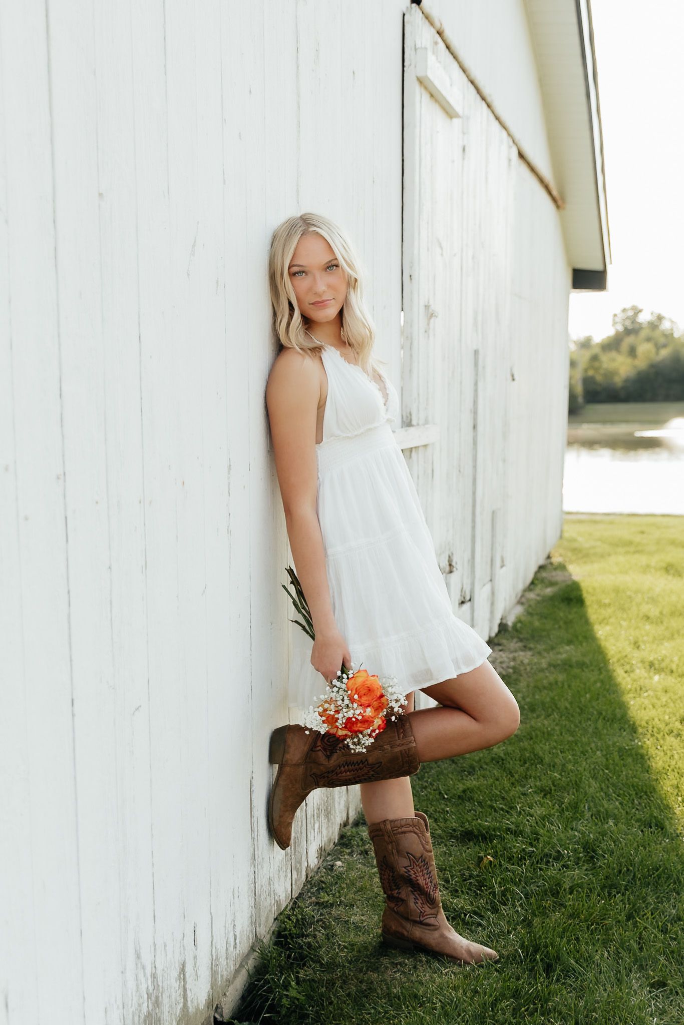 Dreamy golden hour senior portraits in Heartland, Michigan with a beautiful white barn setting. By Brena B Imagery
