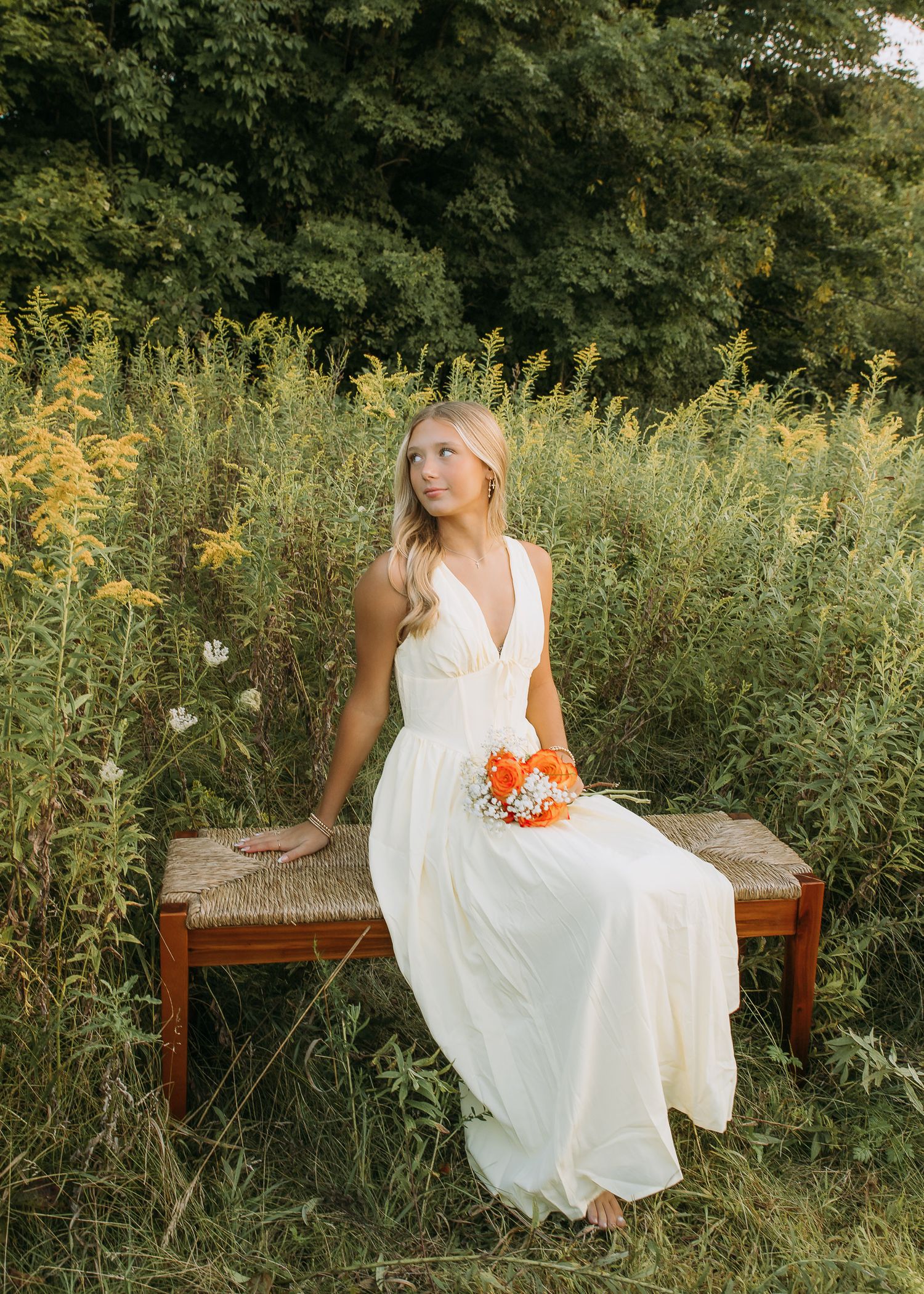 Dreamy golden hour senior photography session by Howell, Mi Senior Photographer Brena B Imagery. Senior sits on bench in field. Senior Inspo