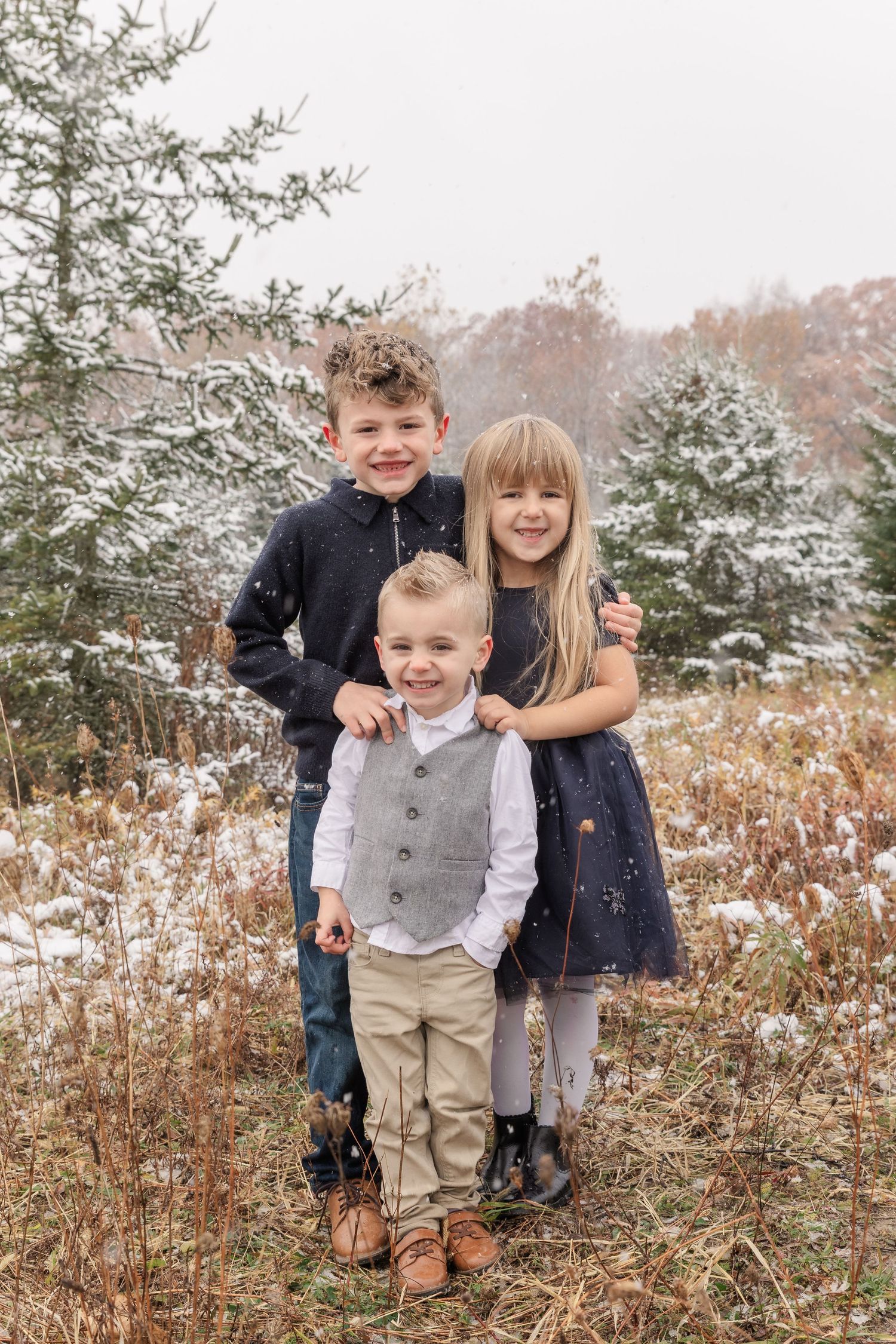 Family portrait session in Fenton, Michigan during winter at a Christmas tree farm, children smiling, photographed by Brena B Imagery.