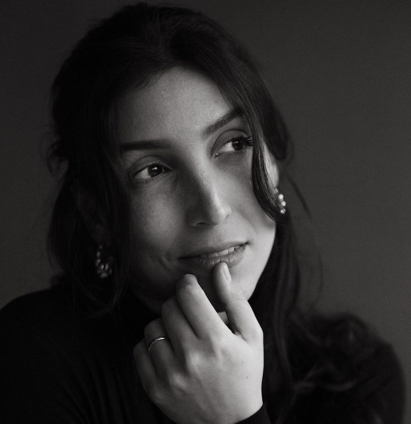 Black and white portrait of a young woman with dark hair resting her chin on her hand.