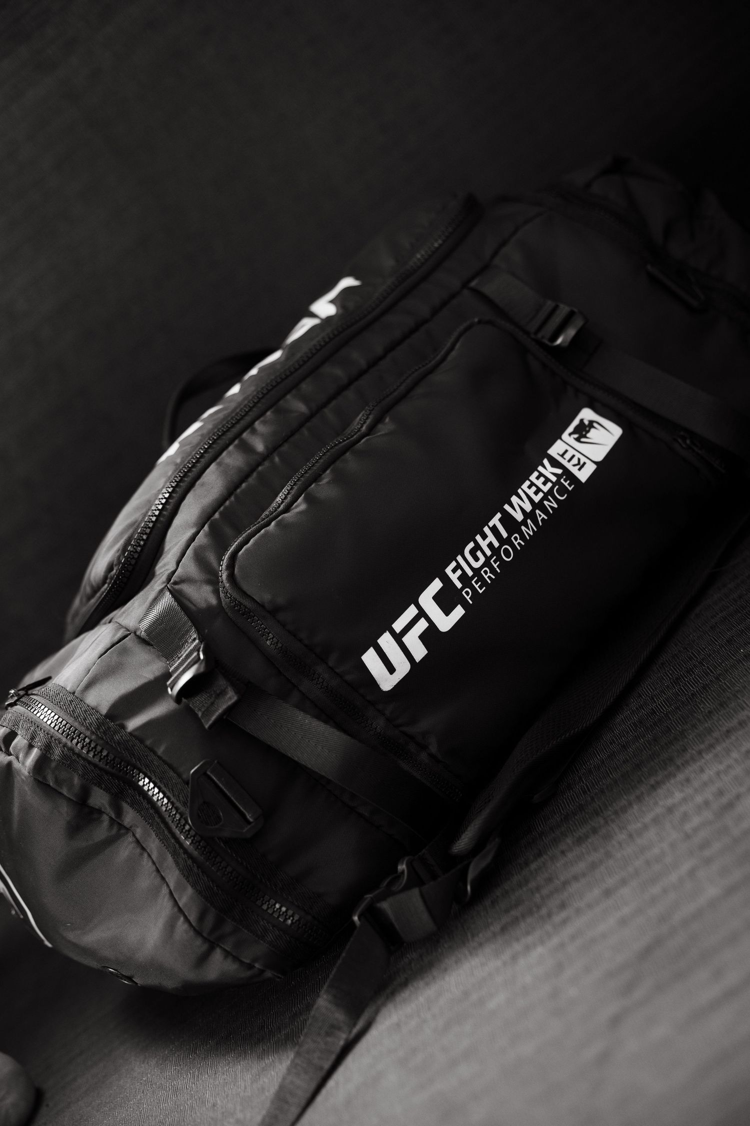 Black UFC Fight Week Performance duffel bag on dark surface, monochrome photo.