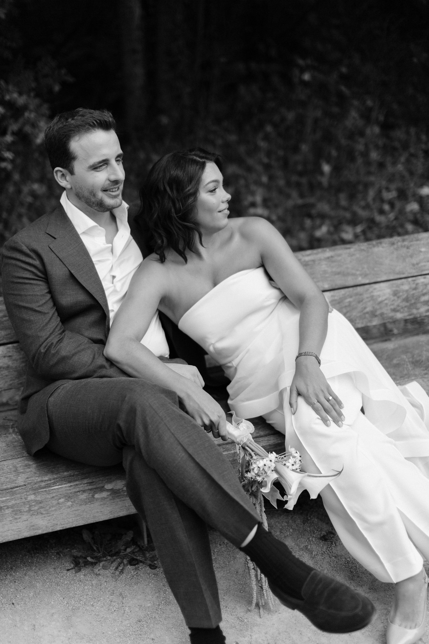 A romantic black and white wedding photo series showing a couple sitting together on steps in intimate poses.