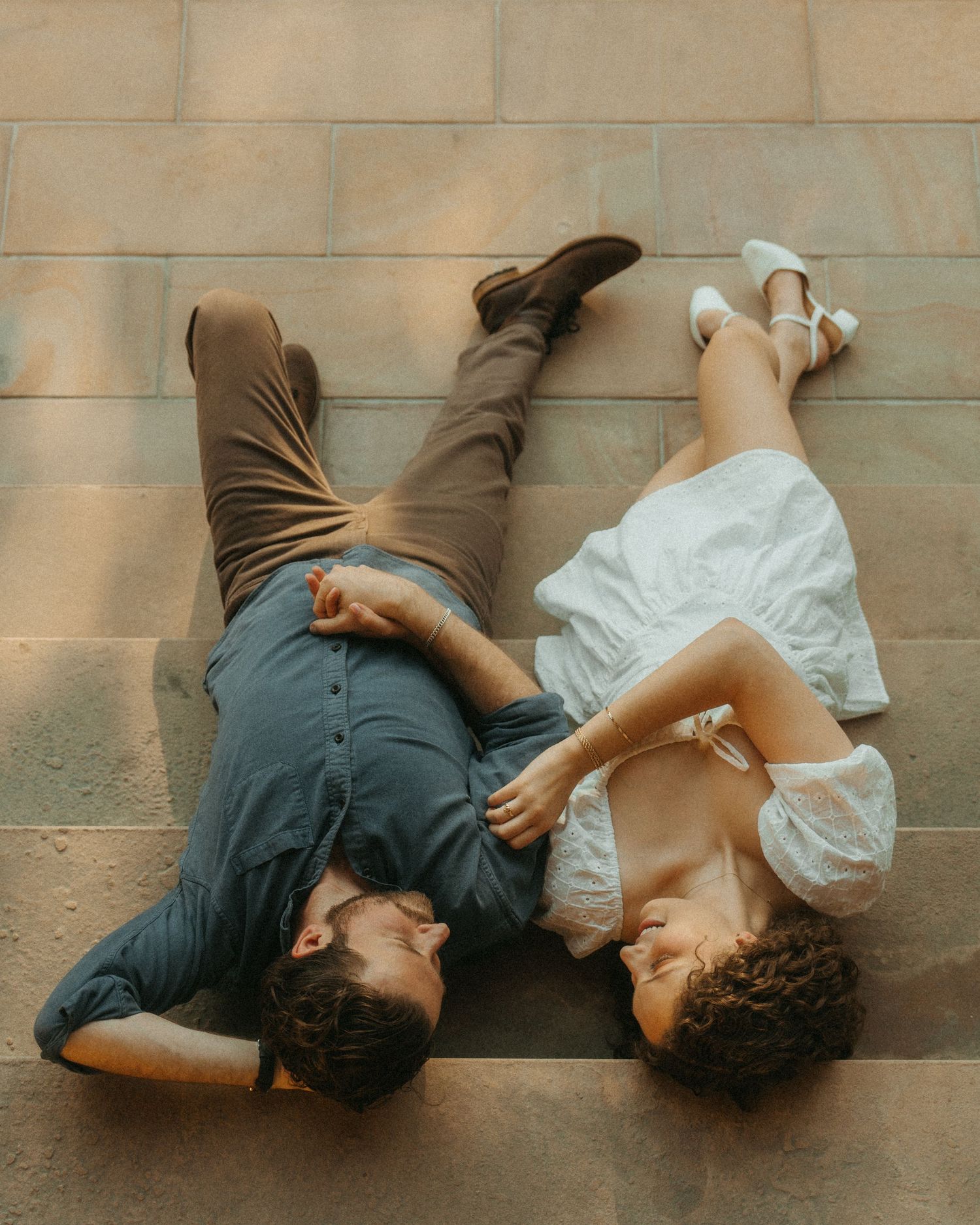 Two people lying on wooden floor looking at each other in sequence of romantic candid lifestyle photos.