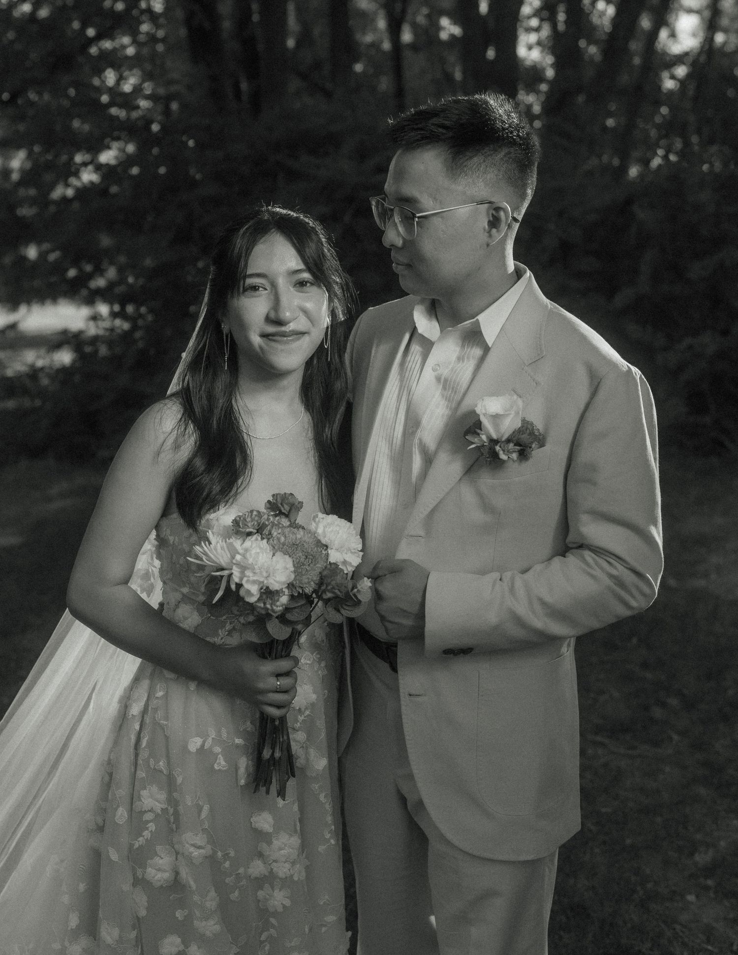 A romantic black and white wedding photo series showing a couple embracing in a wooded outdoor setting.