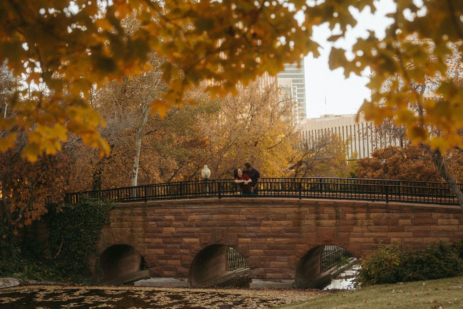 A scenic autumn landscape with golden leaves and brick walls along a park path in an urban setting.