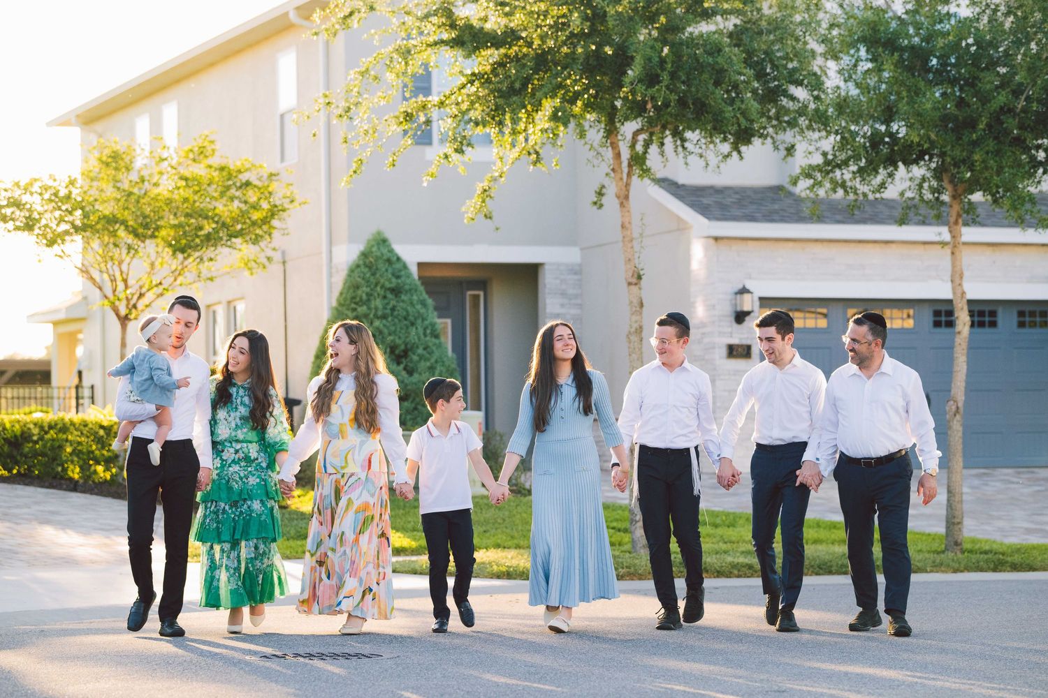 Group walking together on a sidewalk during a sunset photoshoot in a residential area.