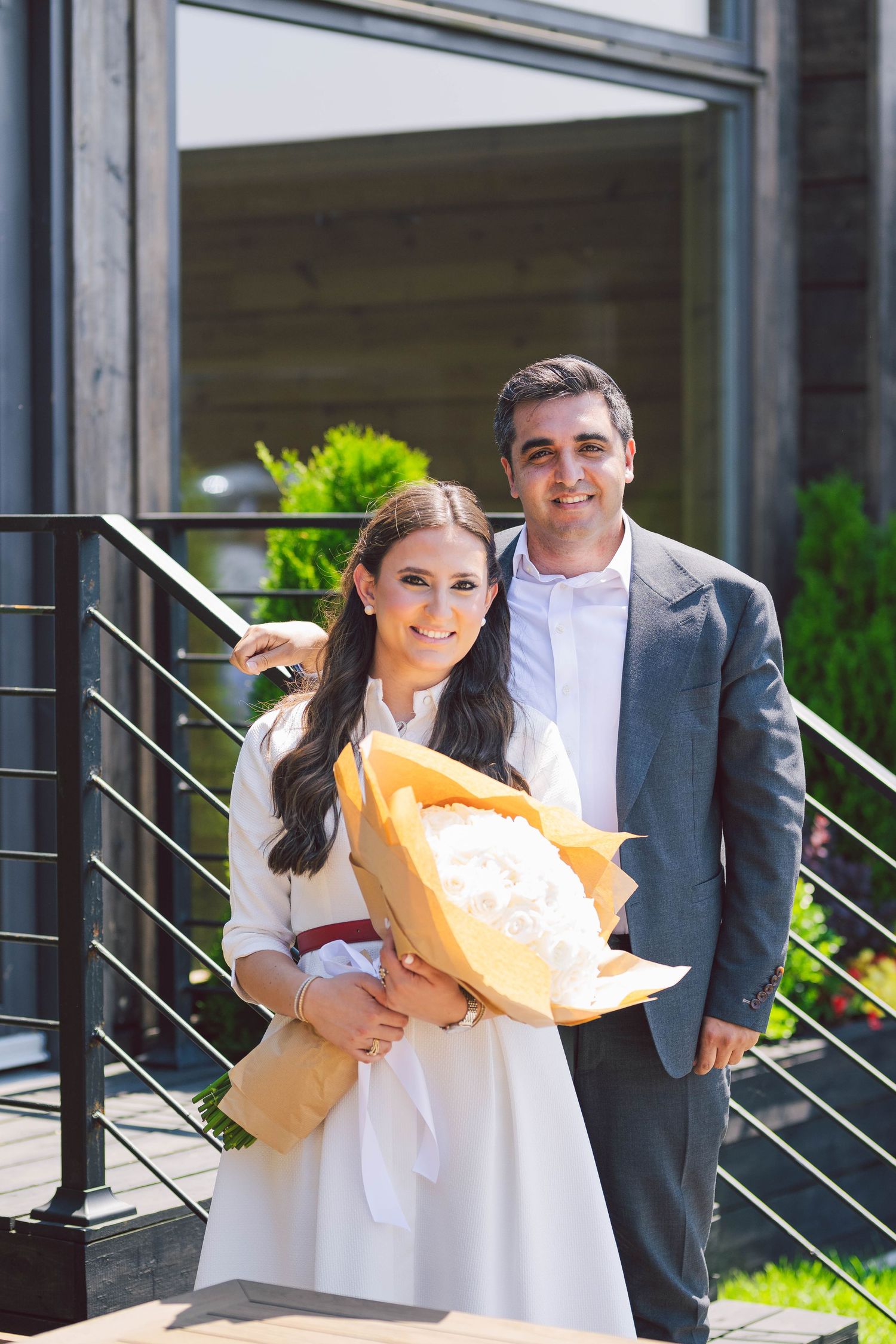 Couple holding decorative items while standing in front of metal railings outdoors.