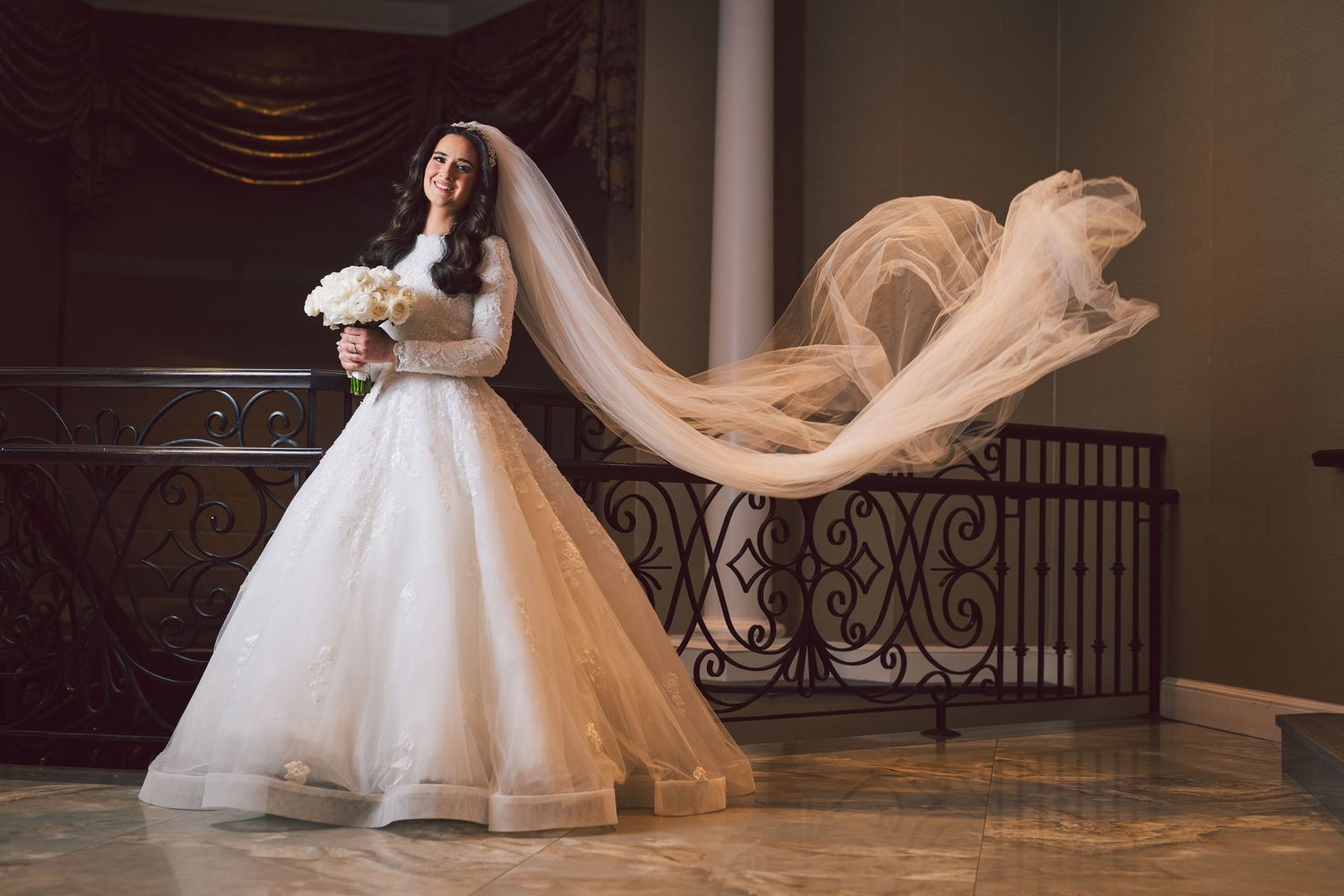 Elegant wedding dress with full skirt captured in dramatic indoor setting.