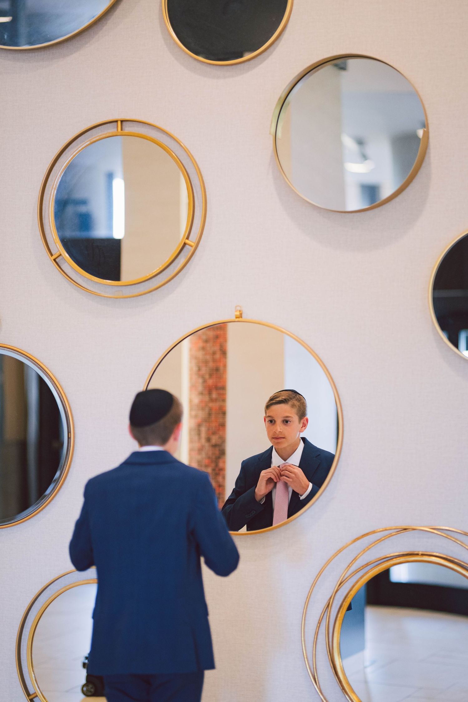 Multiple circular gold-framed mirrors arranged on a white wall create an artistic display.