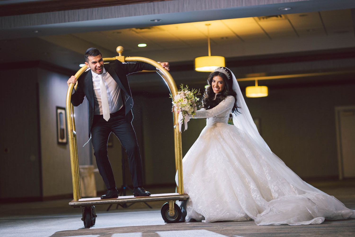 Elegant wedding couple poses in atmospheric indoor setting.