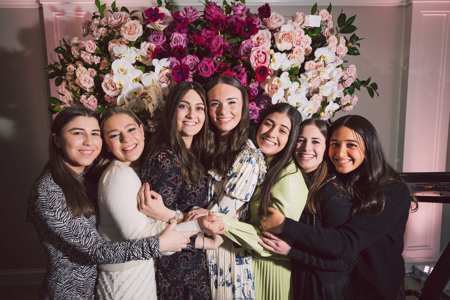 A group celebration photo with beautiful floral decorations and pink lighting.