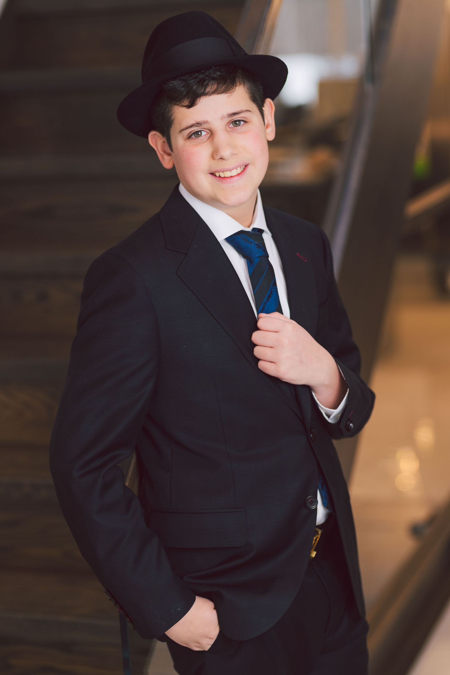 Classic portrait of young person in black suit, tie and fedora.