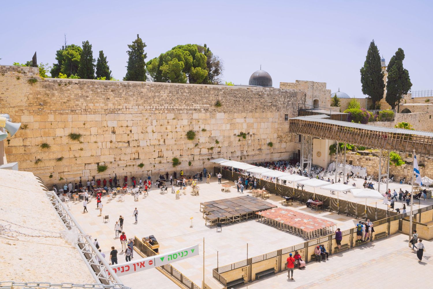 Aerial view of the Western Wall plaza in Jerusalem showing ancient stone walls and visitors gathering below.