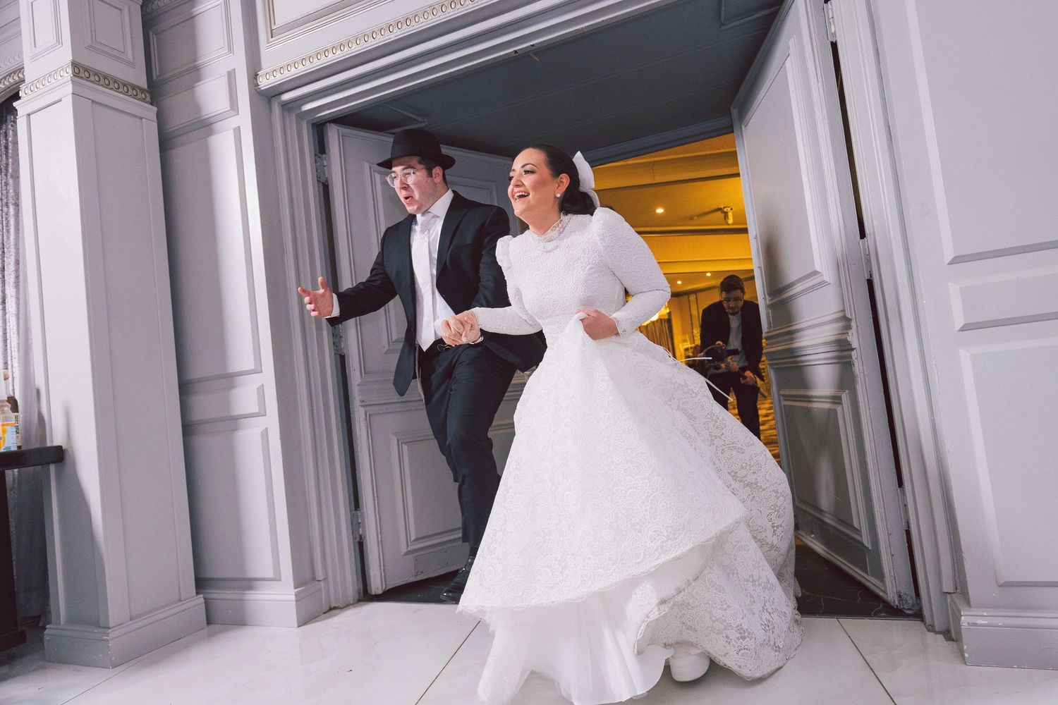 A wedding celebration moment captured in an elegant hallway with white columns.