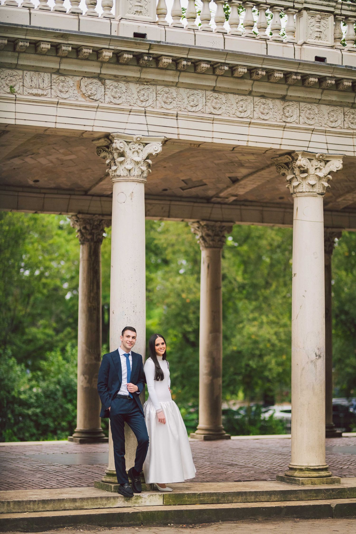 Architectural engagement photos featuring a classic colonnade with ornate stone details and green backdrop.